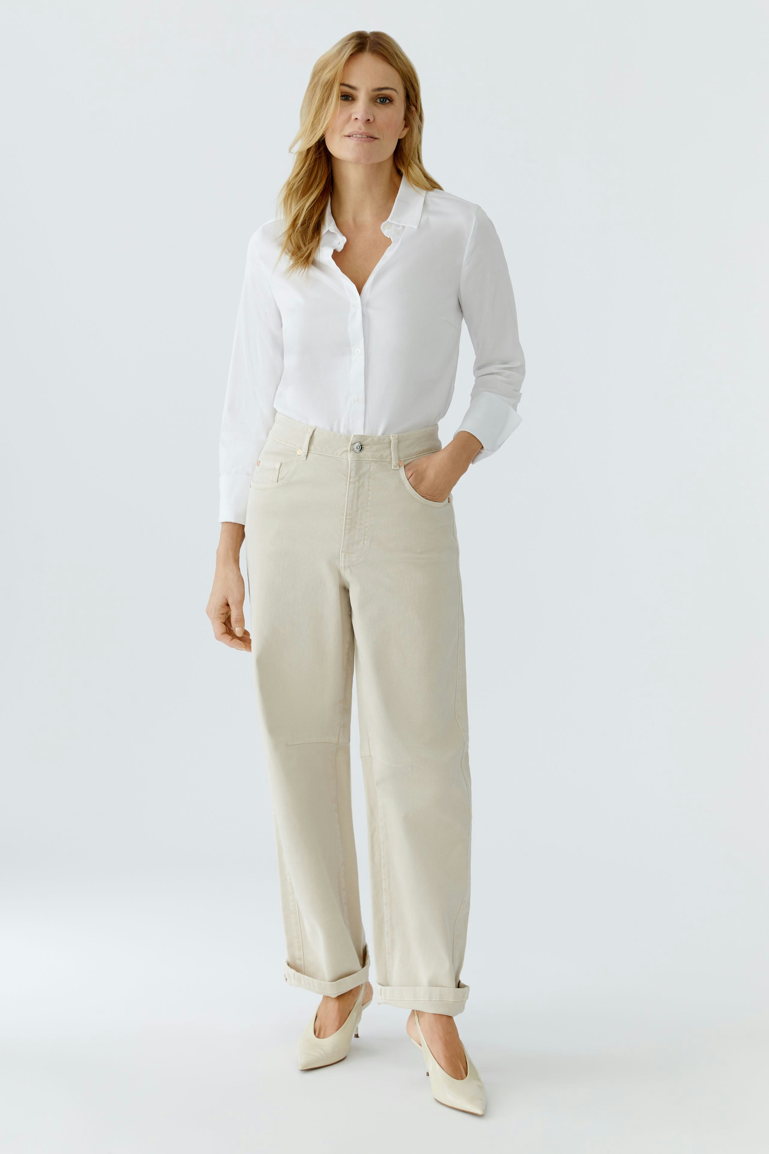 Casual women's jeans barrel: A woman in light-colored jeans with a white shirt stands confidently.