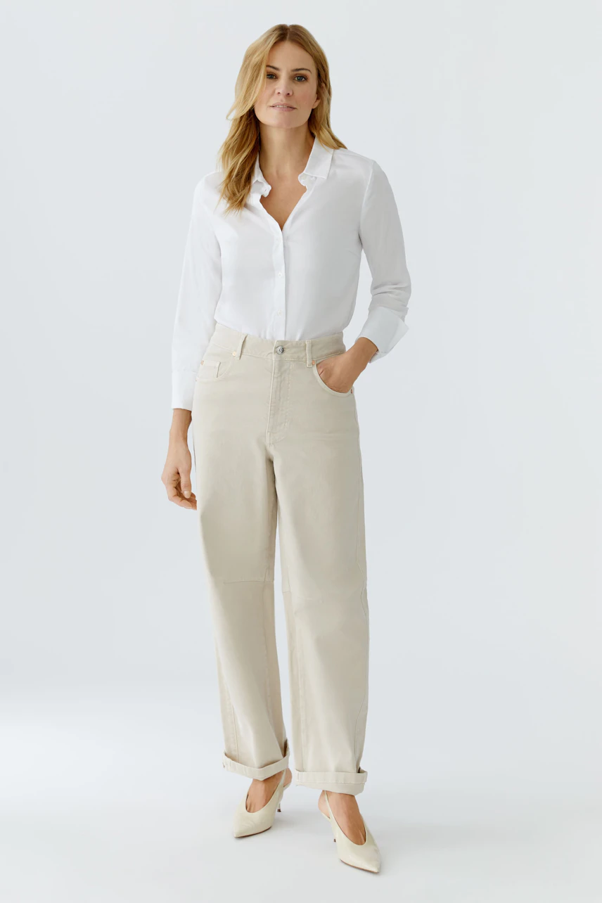 Casual women's jeans barrel: A woman in light-colored jeans with a white shirt stands confidently.