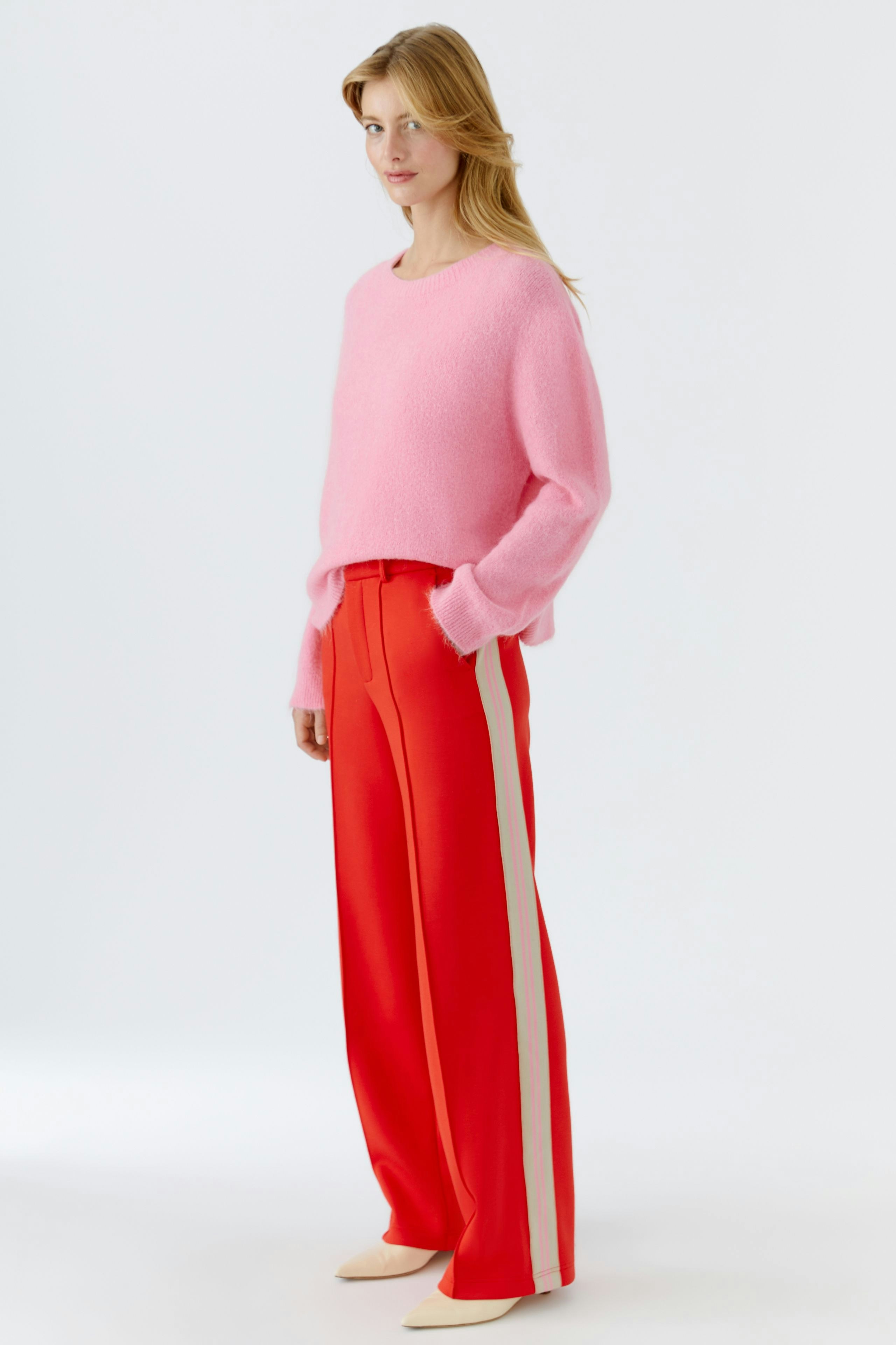 Bequeme Damen-Hose: Frau in roten, weiten Hosen mit seitlichen Streifen steht lässig und selbstbewusst.