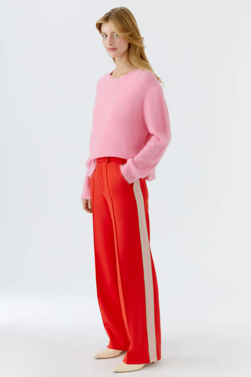 Bequeme Damen-Hose: Frau in roten, weiten Hosen mit seitlichen Streifen steht lässig und selbstbewusst.