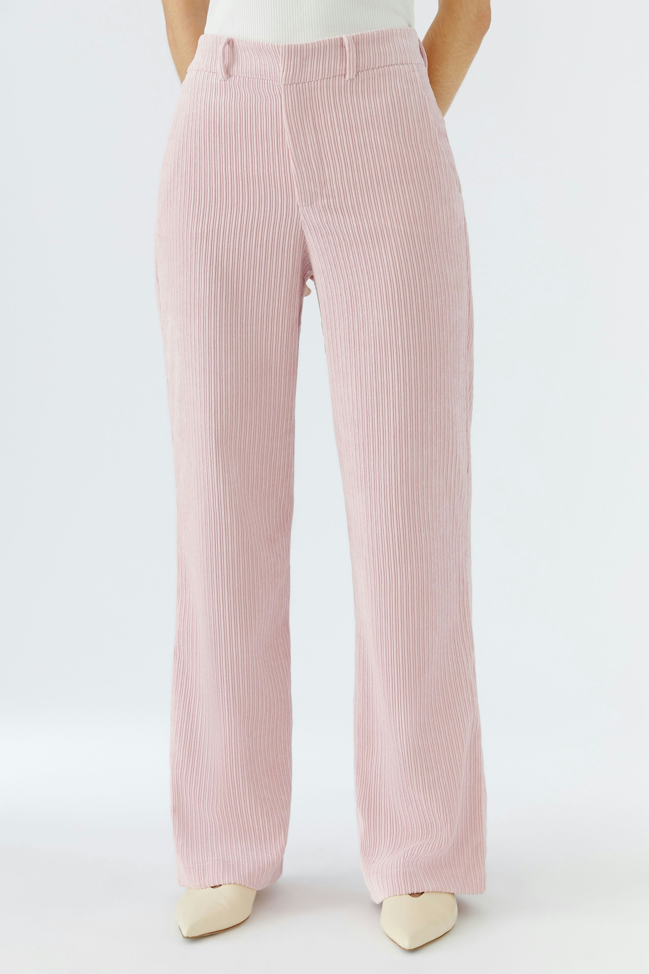 Moderne Cordhose: Frau trägt eine rosa Cordhose mit geradem Schnitt und lässigem Look.