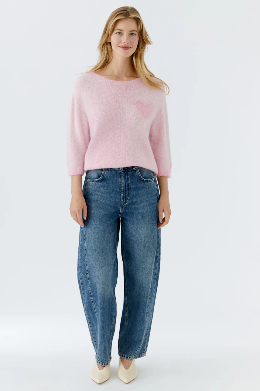 Damen-Pullover in zartem Rosa mit Herz-Applikation, lässig kombiniert mit Jeans.