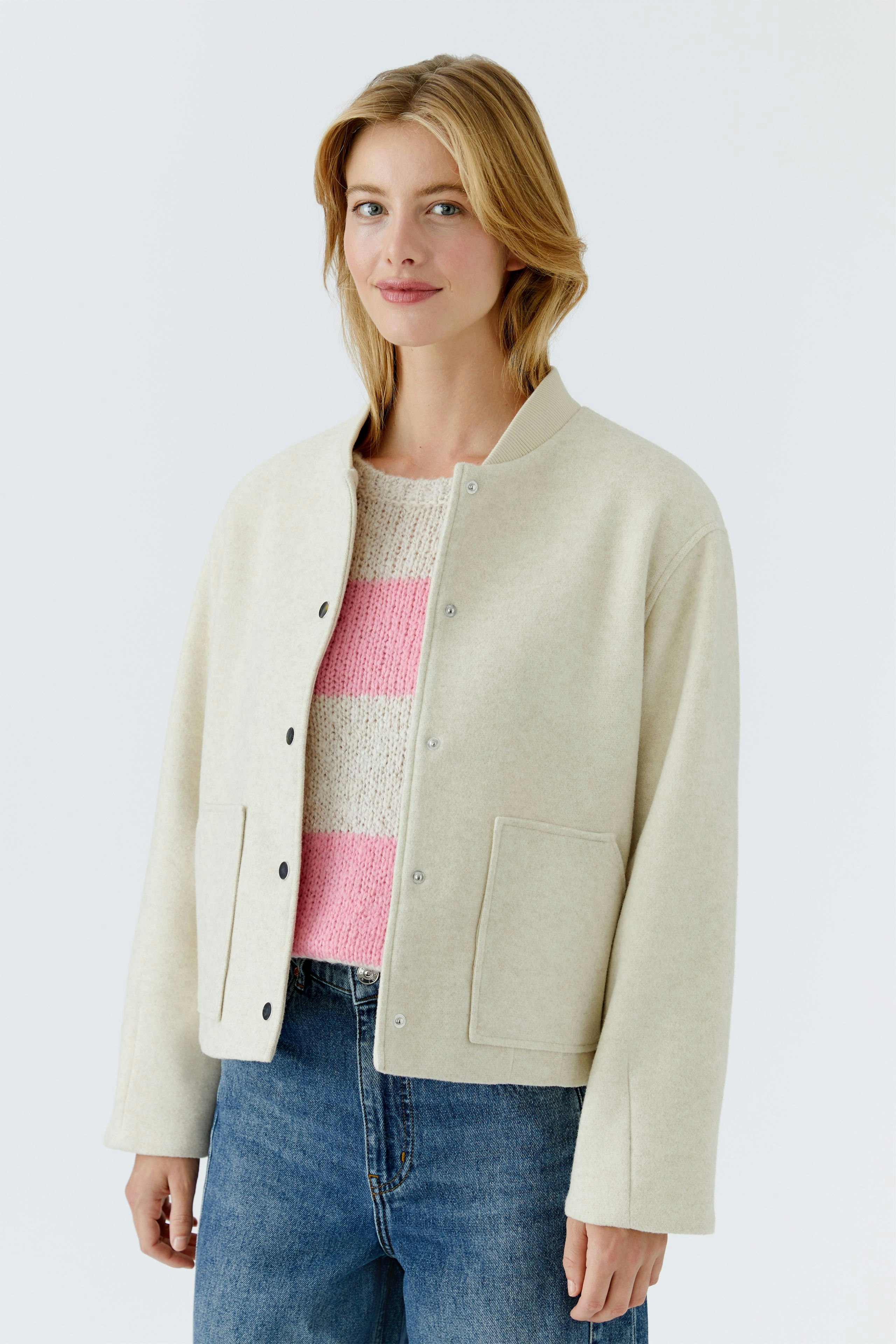Casual women's blouson: A woman in a cream-colored jacket over a striped pullover and jeans.