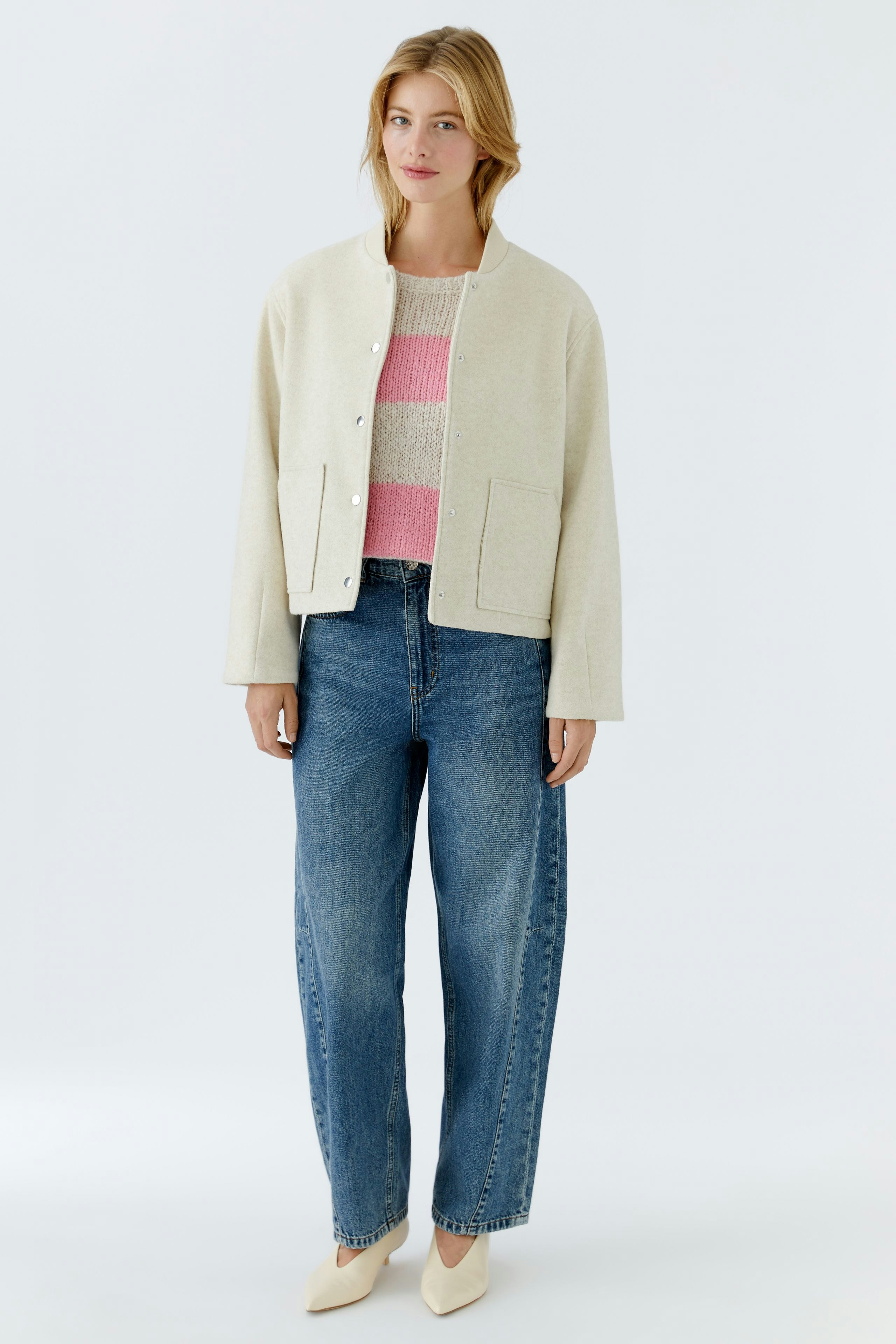 Casual women's blouson: A woman in a light beige jacket over a pink striped pullover and blue jeans.
