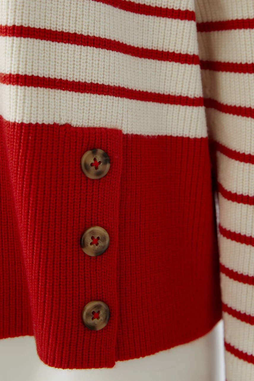 Casual women's pullover: Close-up of a striped pullover with red and white colors and button details.