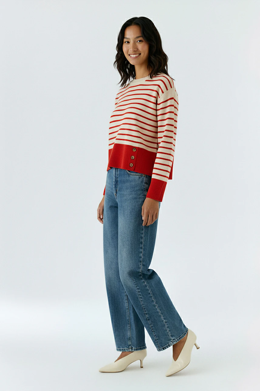 Casual women's pullover: Smiling woman in a striped pullover with red accents and wide jeans.