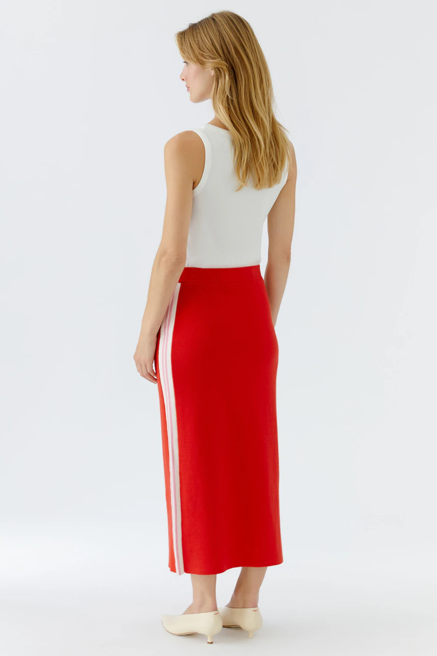 Casual women's knit skirt: A woman in a red knit skirt with white stripes, viewed from the back.