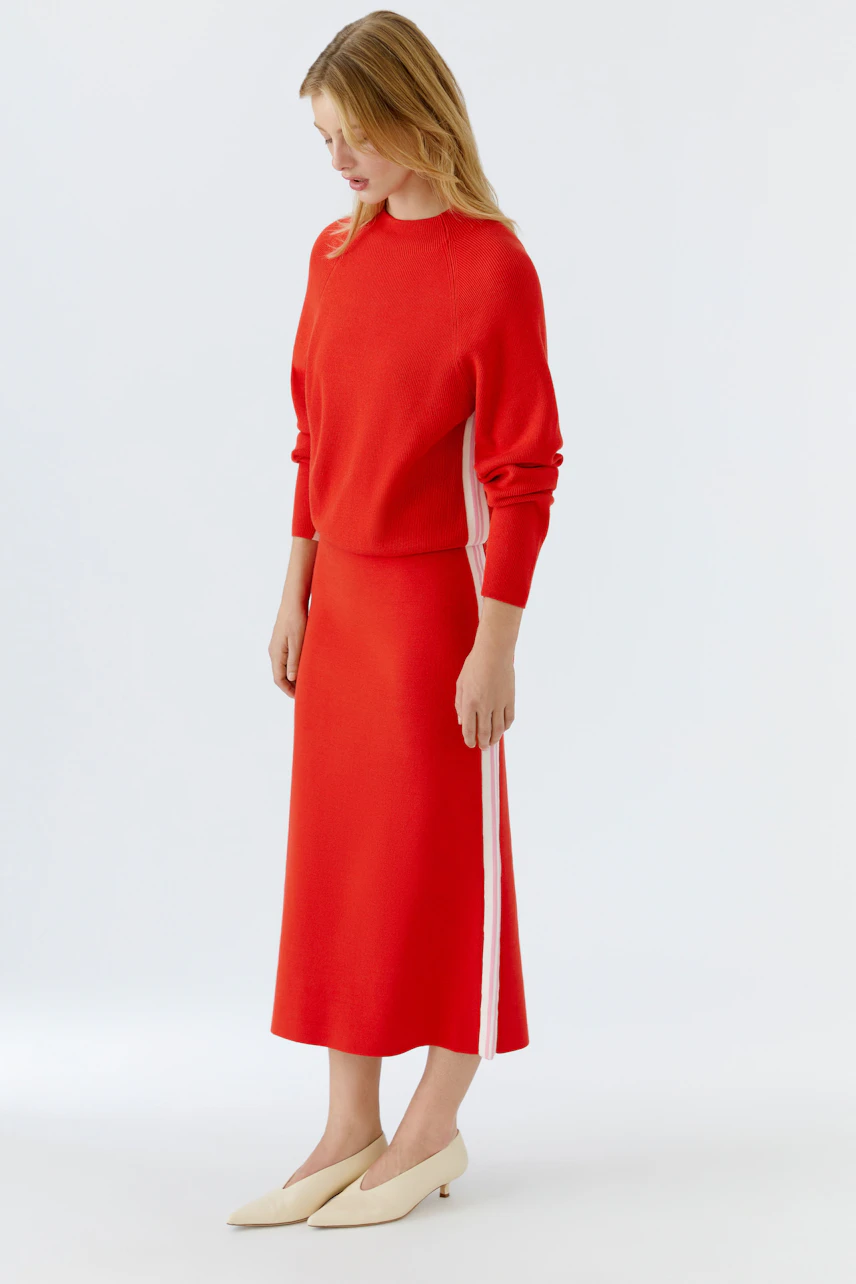 Casual women's knit skirt in vibrant red with side stripes, worn by a woman.