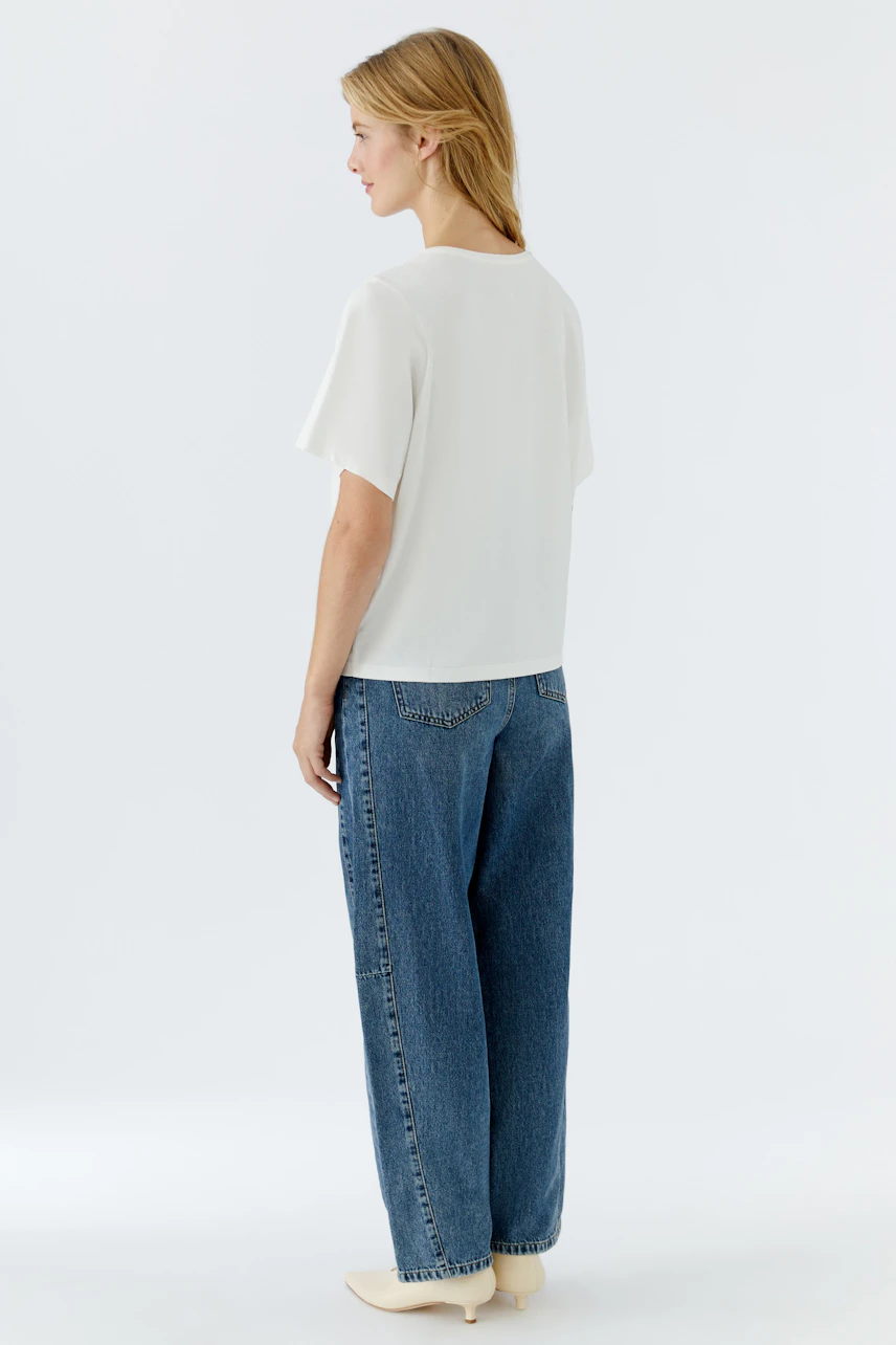Casual women's T-shirt: Young woman in a white top paired with relaxed-fit jeans.