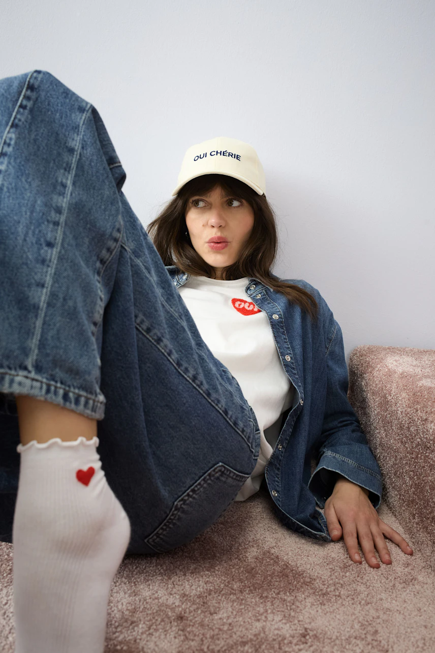 Casual women's T-shirt: Young woman in a white T-shirt with a red logo, paired with denim.