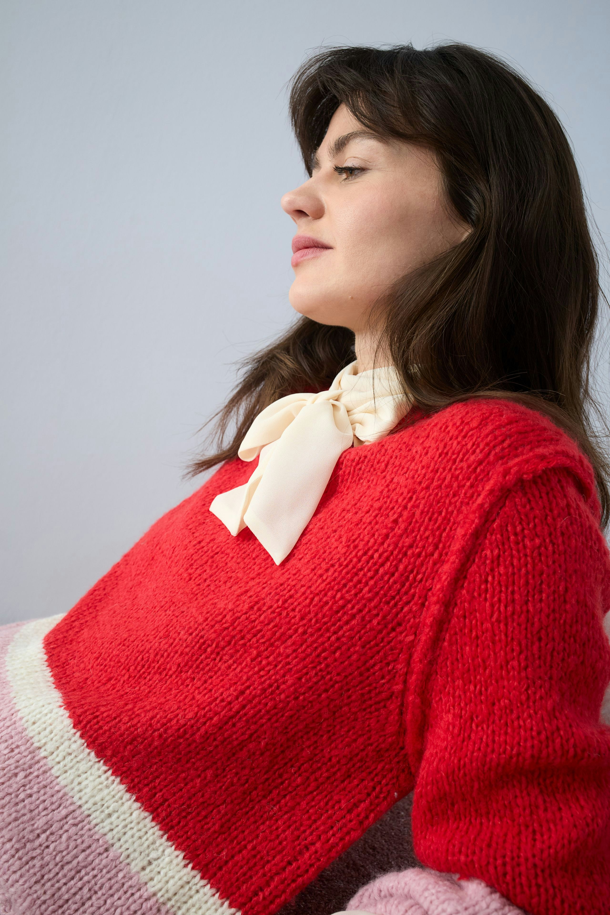 Casual women's blouse: Woman in a vibrant red knit blouse with a stylish bow detail.