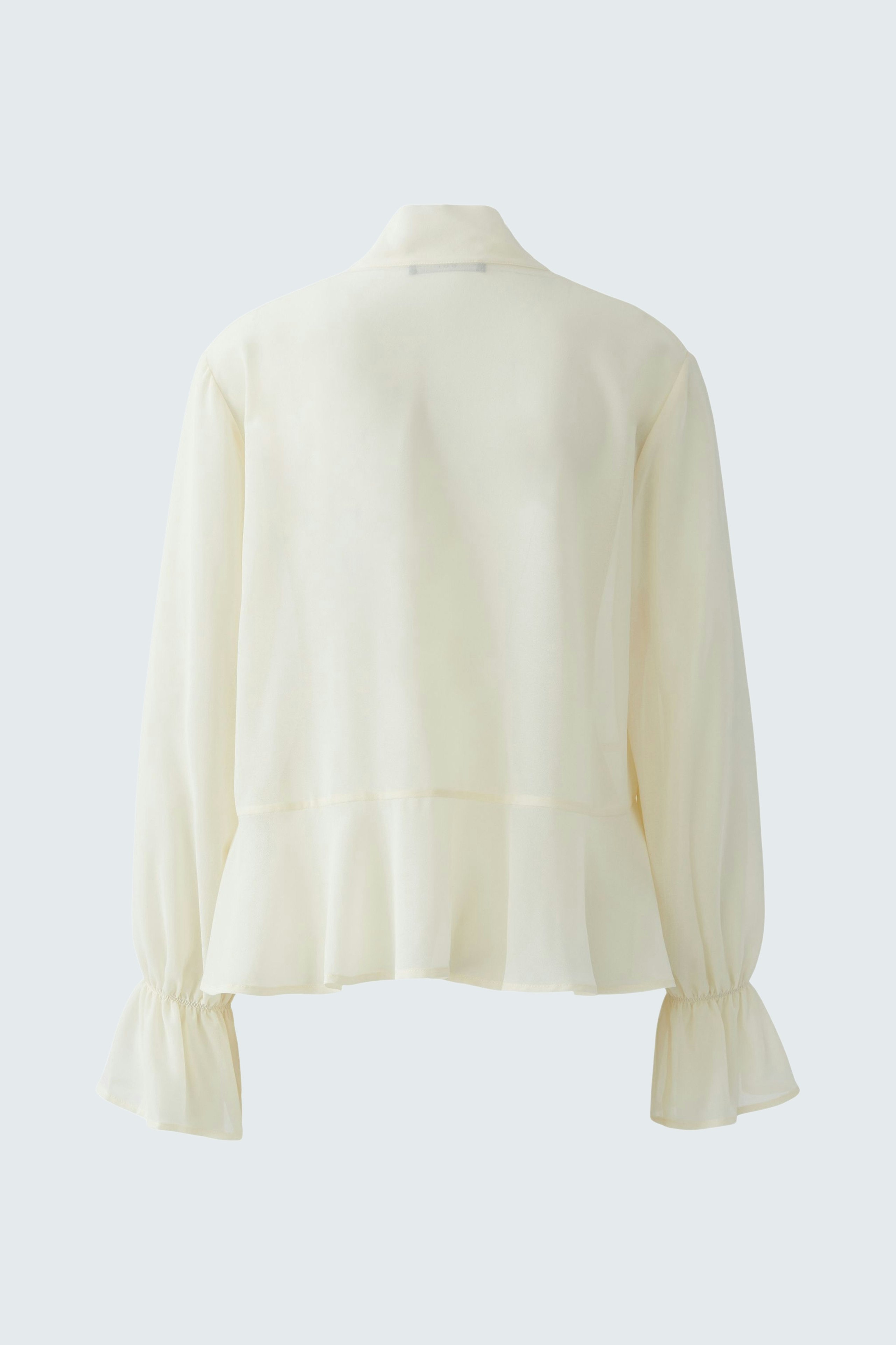 Casual women's blouse: A woman in a light cream blouse with flared sleeves, showcasing a relaxed style.