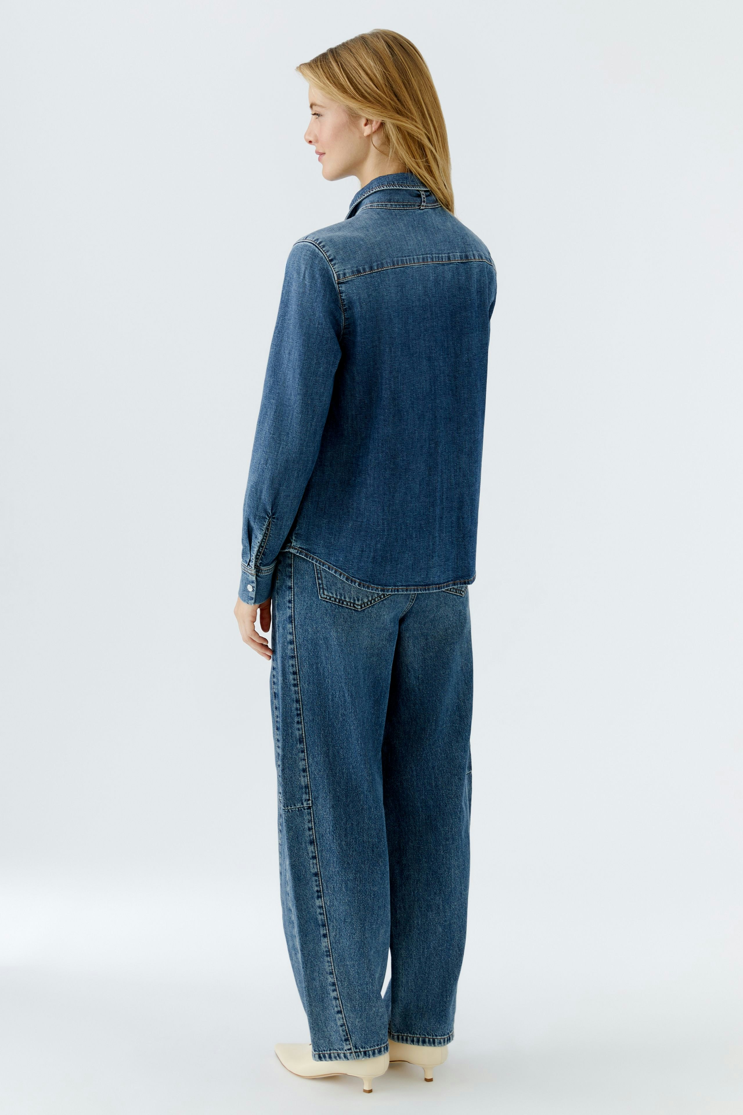 Casual women's denim shirt: A woman in a blue jeans shirt with a relaxed fit, showcasing a simple design.