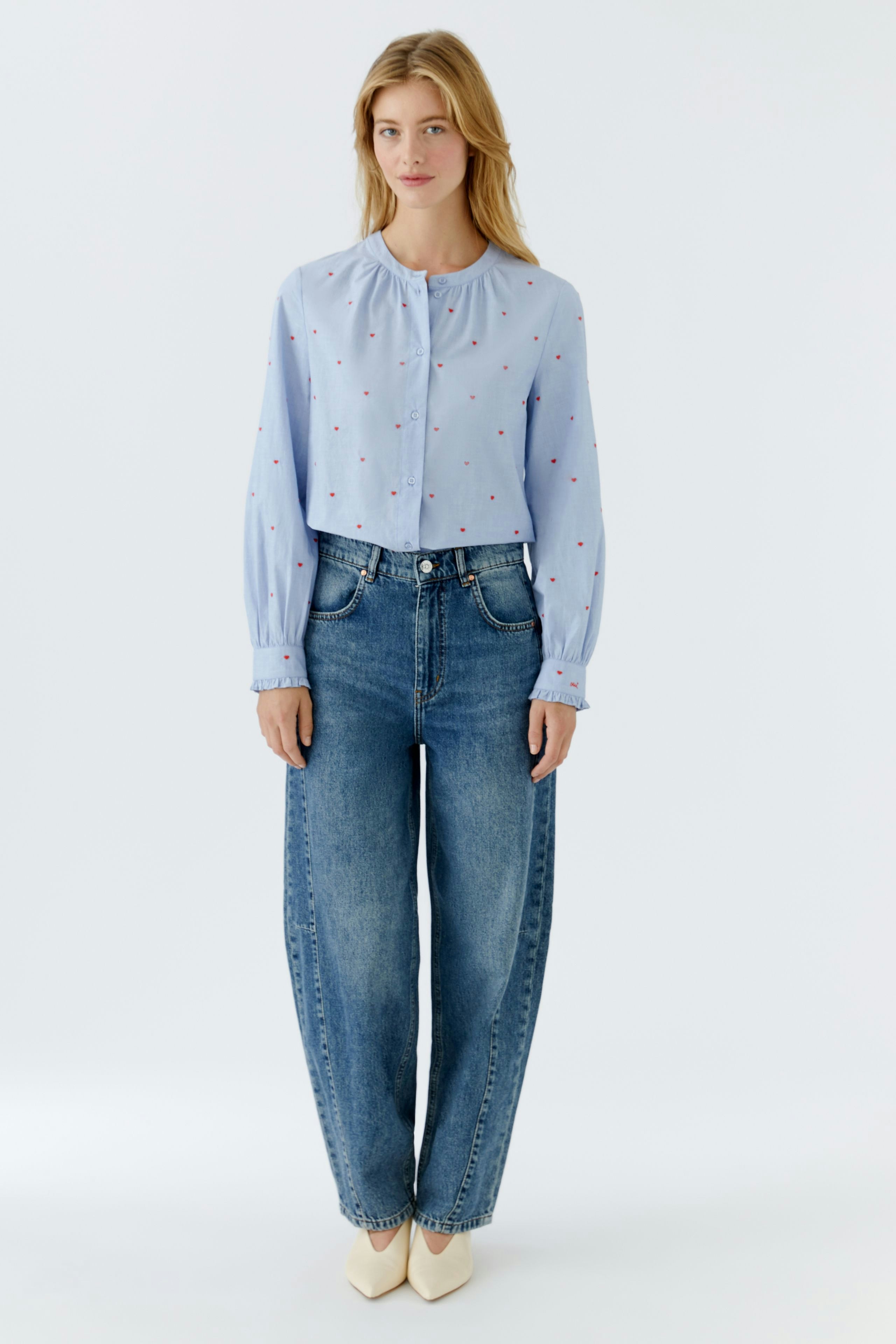 Casual women's blouse: A woman in a light blue blouse with small red dots and relaxed-fit jeans.