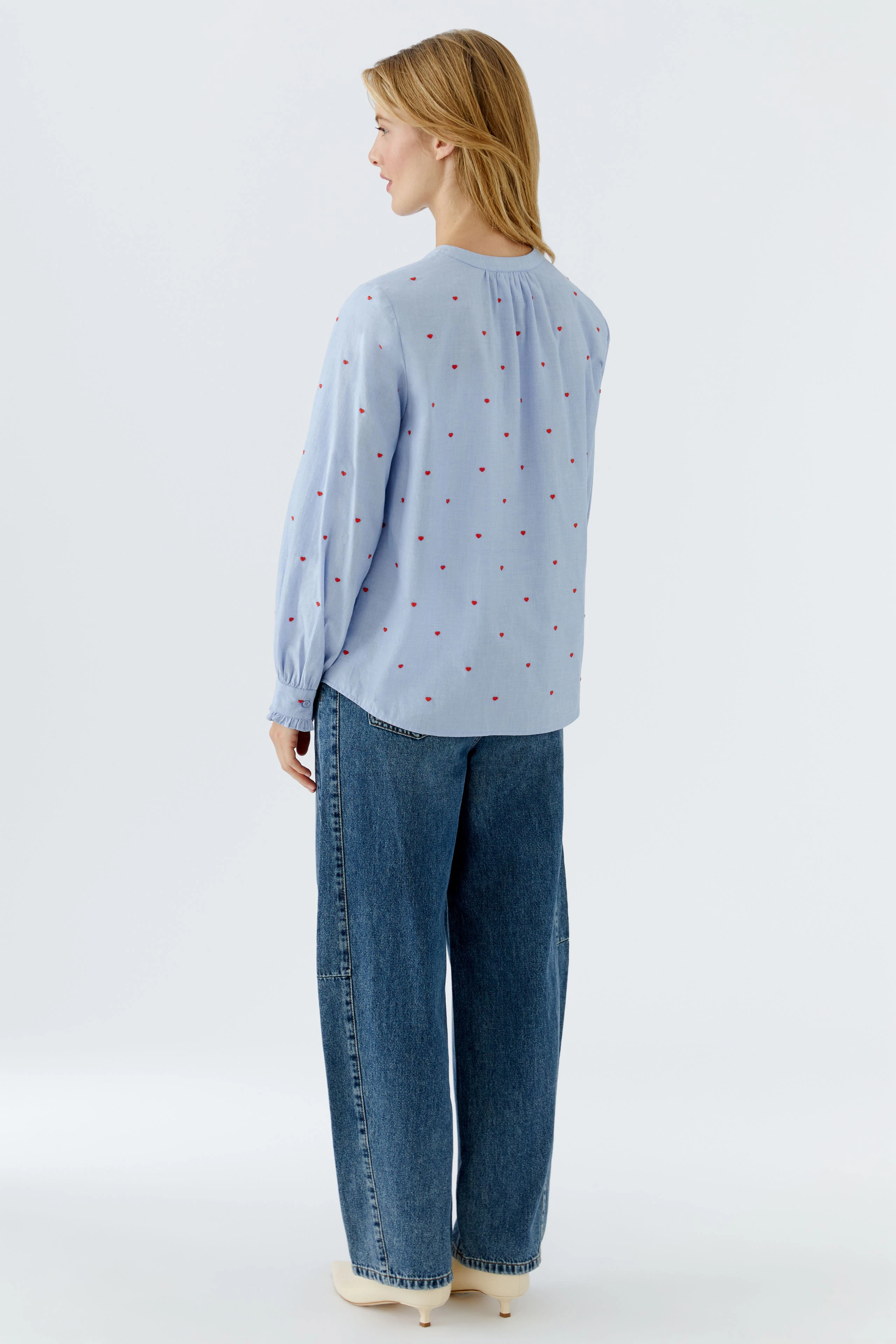 Lässige Damen-Bluse: Frau mit blauer Bluse mit roten Punkten und lockeren Jeans von hinten.