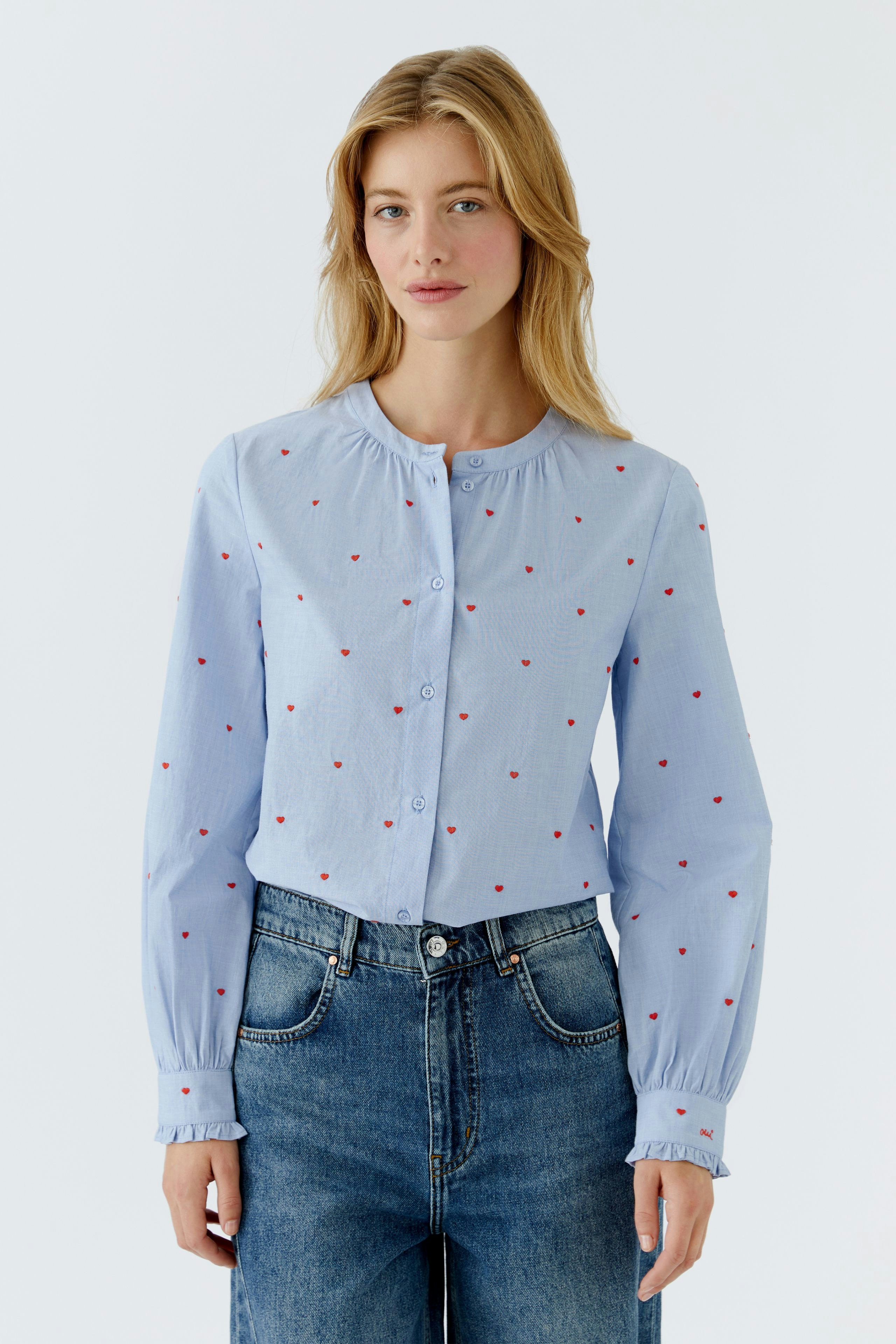 Light blue blouse with red dots: Woman wearing a button-up shirt with a relaxed fit.