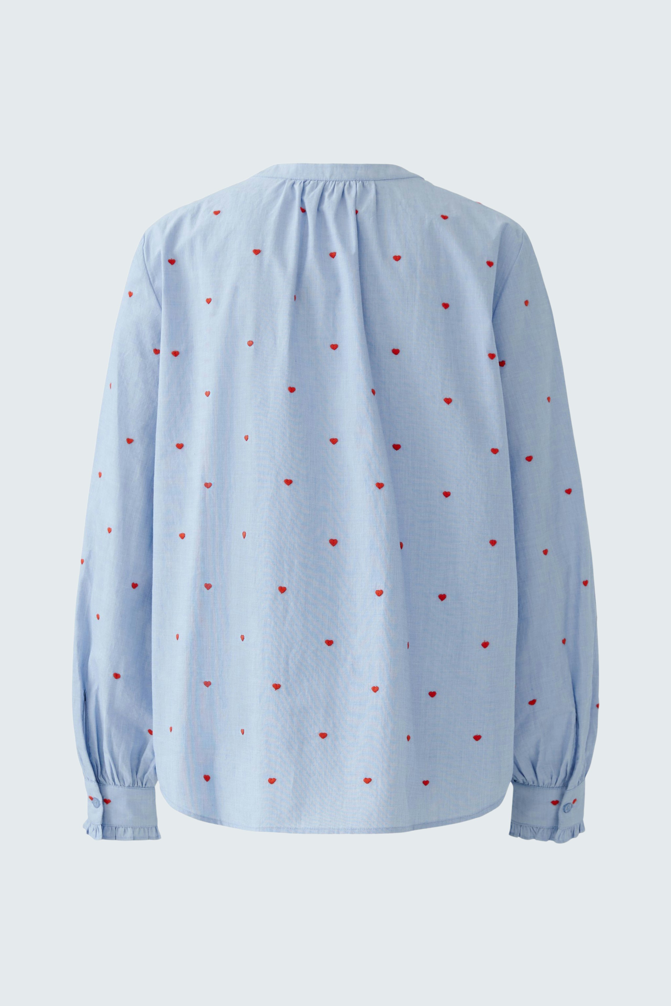 Light blue blouse with red dots, featuring a relaxed fit and long sleeves.