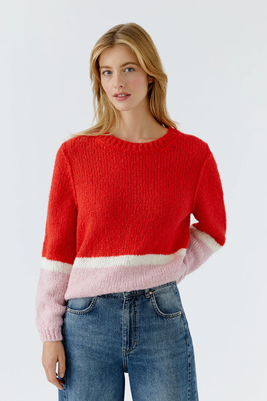 Casual women's pullover: Young woman in a red and pink knitted pullover with relaxed fit.