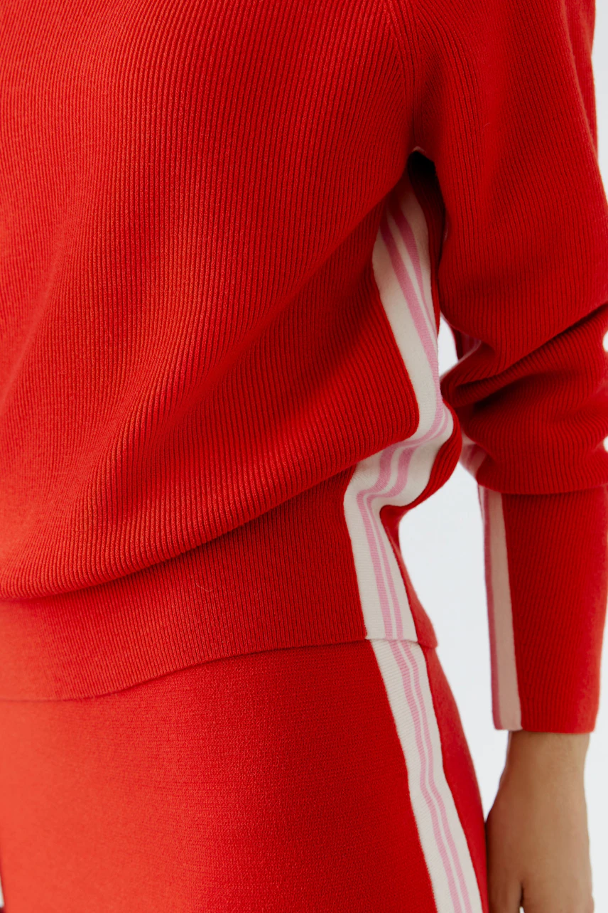 Casual women's pullover: A woman in a red ribbed pullover with white stripes, showcasing a relaxed style.