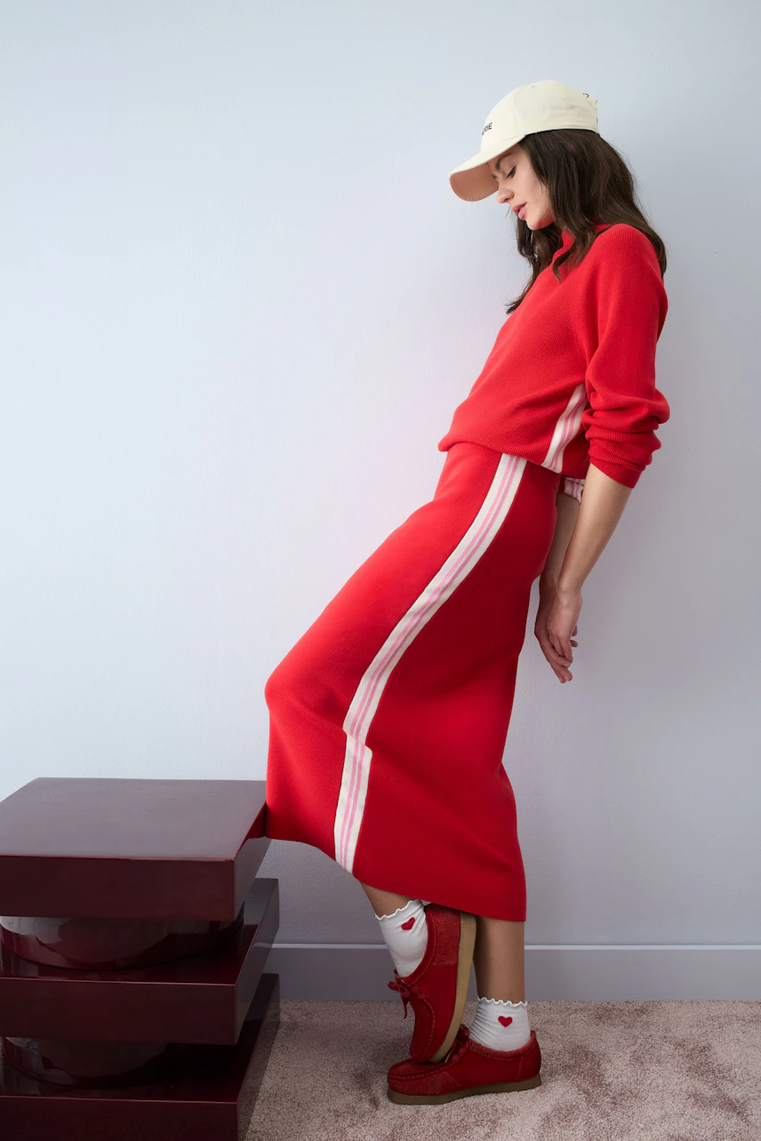 Casual women's pullover: Young woman in a red pullover with white stripes, paired with a matching skirt.