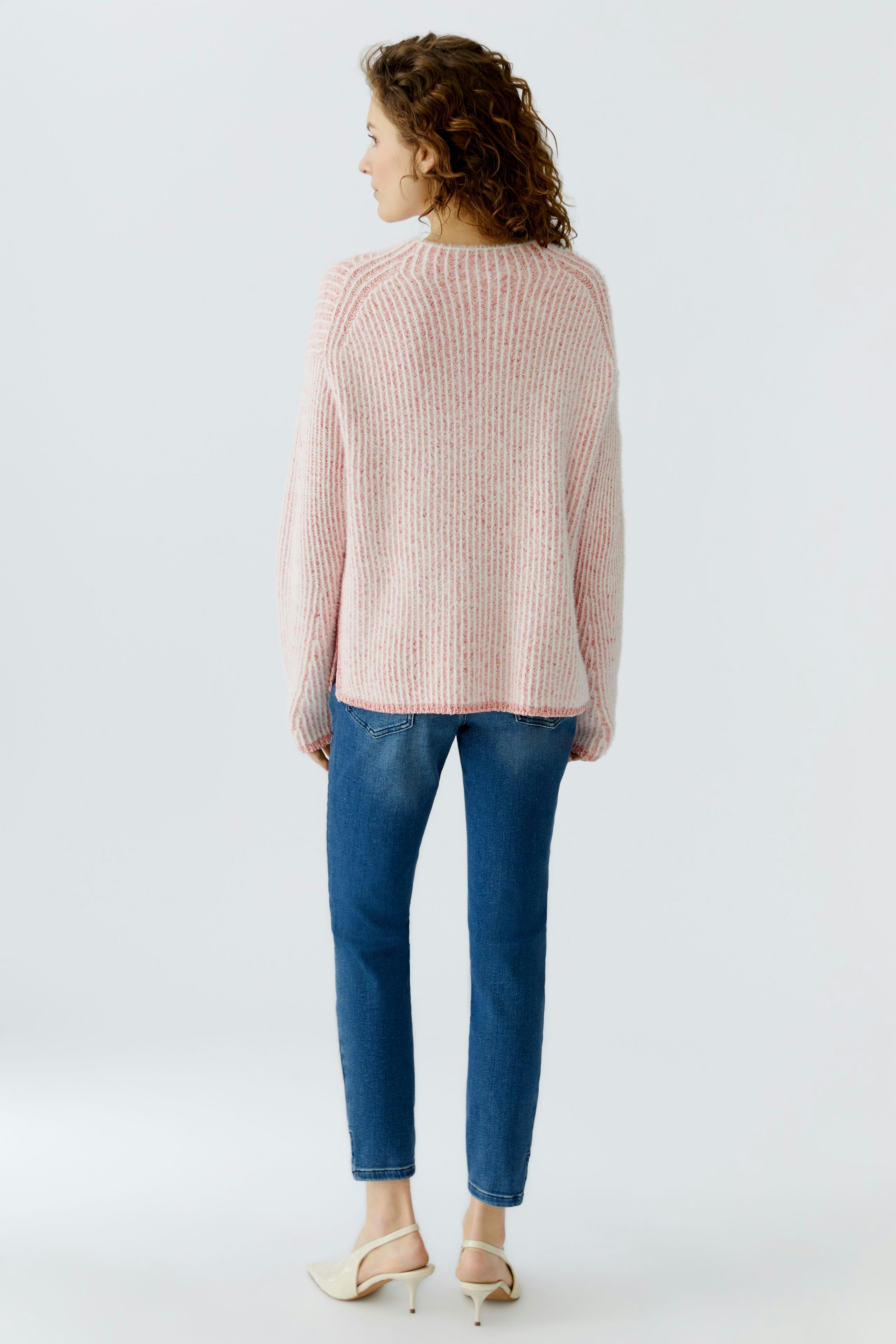 Casual women's pullover: A woman in a pink knitted pullover with a relaxed fit, paired with blue jeans.