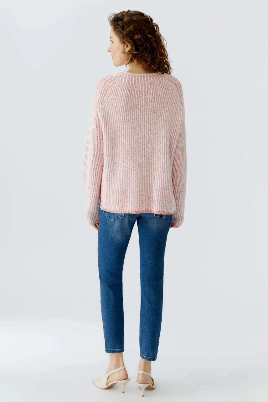 Casual women's pullover: A woman in a pink knitted pullover with a relaxed fit, paired with blue jeans.