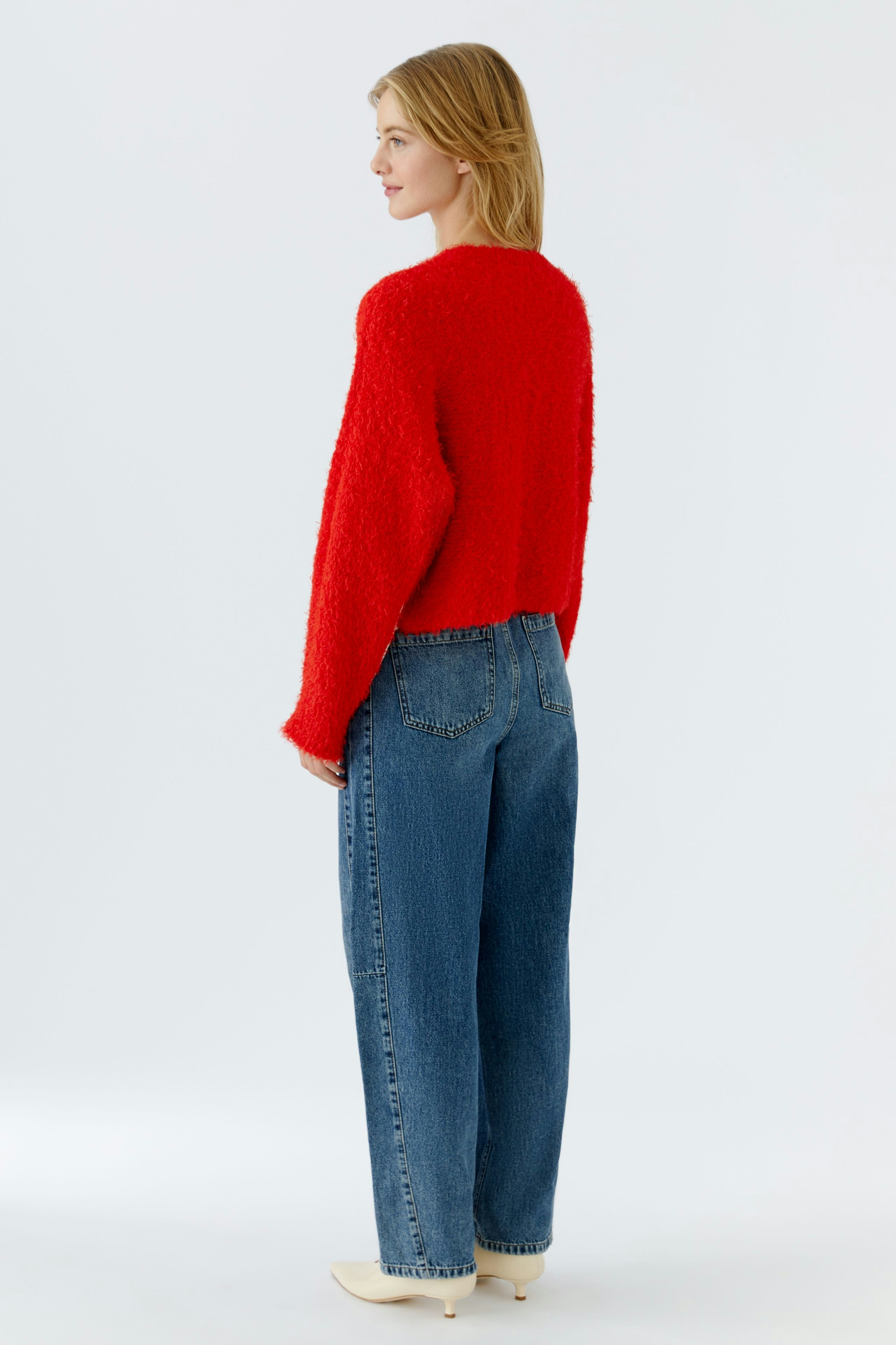 Damen-Pullover: Frau in rotem, flauschigem Pullover mit lässigen Jeans von hinten.