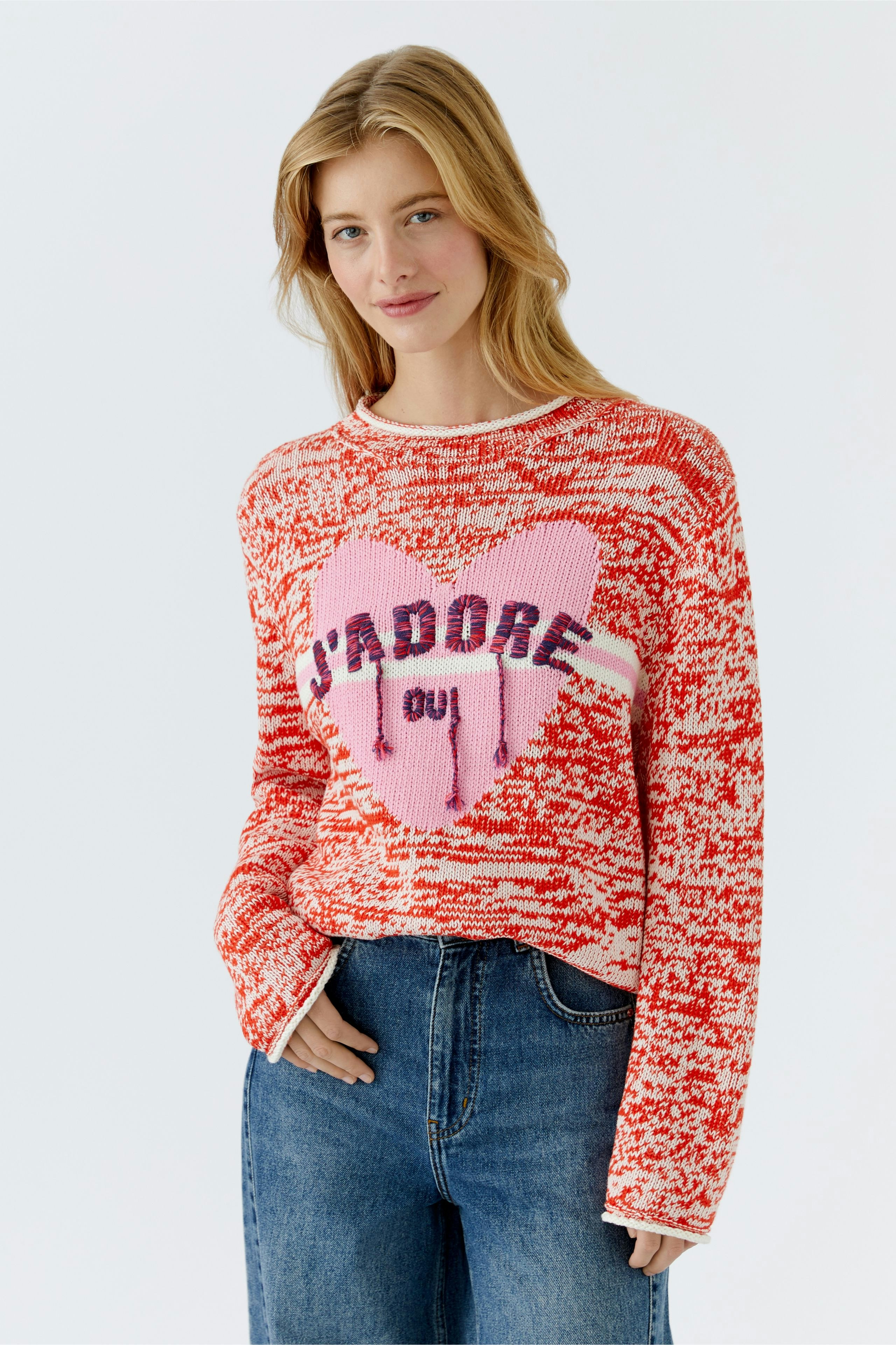 Damen-Pullover in Rot mit Herzmotiv und Schriftzug, lässig kombiniert mit Jeans.