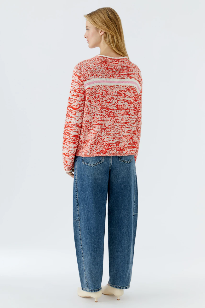 Casual women's pullover: A woman in a red and white patterned pullover with relaxed fit jeans.