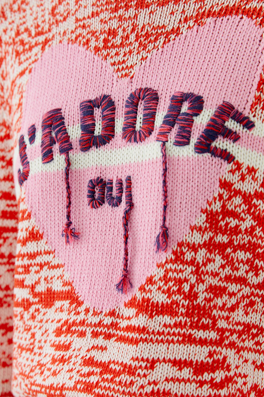 Casual women's pullover: Close-up of a red knit pullover with a pink heart and 'S'ADORE' lettering.