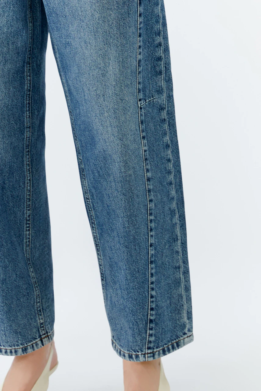 Casual women's jeans: A woman in blue barrel jeans stands confidently, showcasing a relaxed fit.