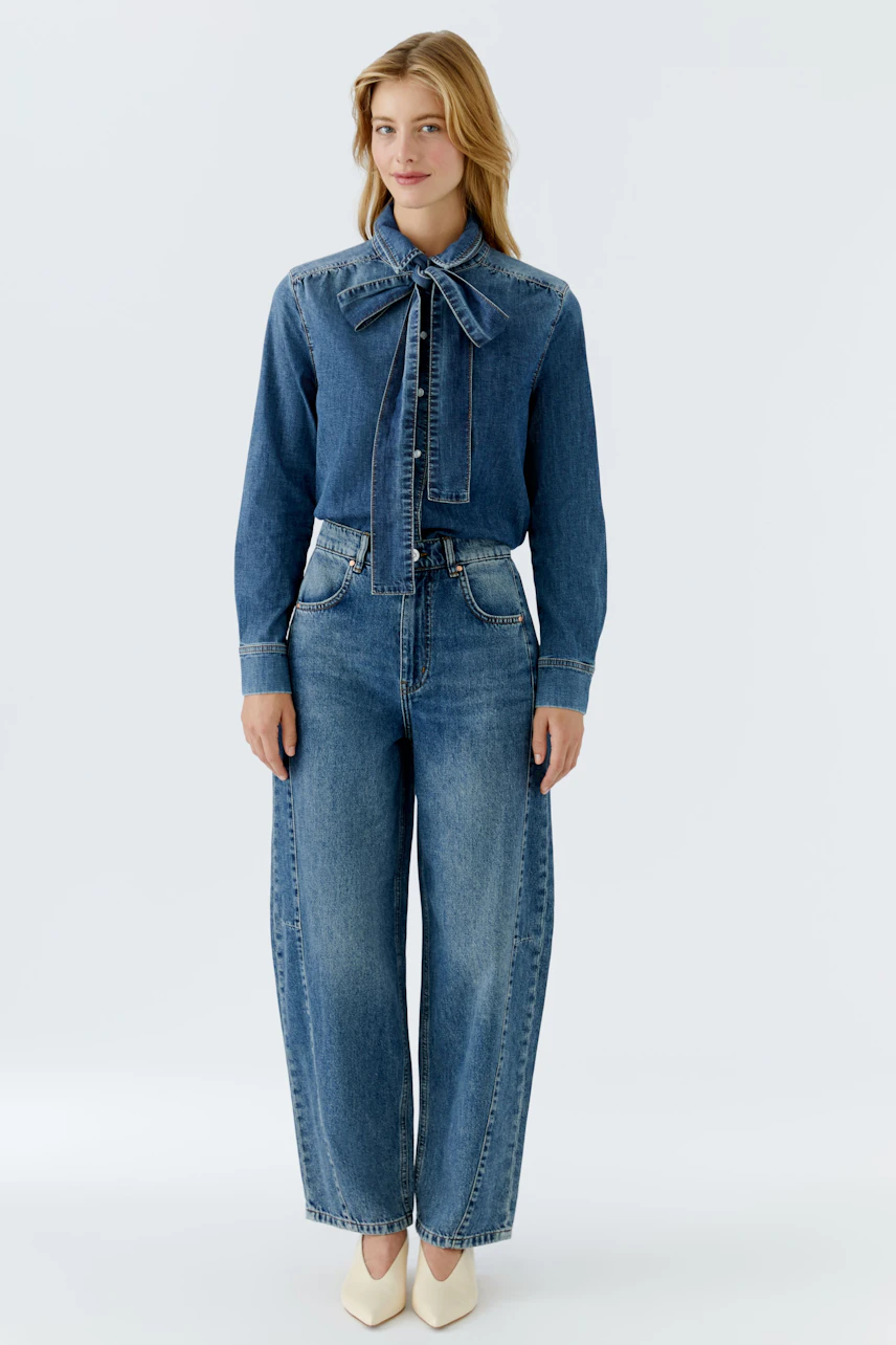 Casual women's jeans barrel: A woman in wide-leg denim jeans with a stylish bow tie blouse.