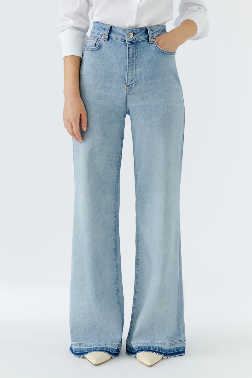 Flared jeans: A woman in light blue flared jeans paired with a white shirt, showcasing a casual style.