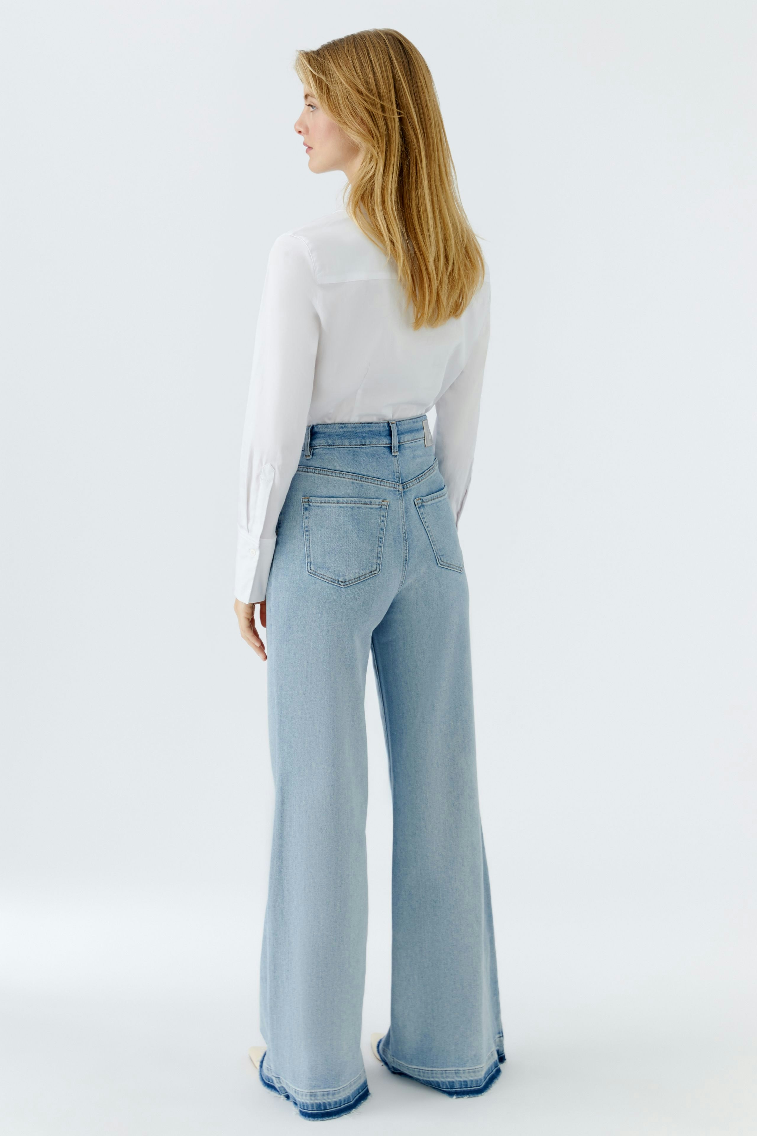 Casual women's flared jeans: A woman in light blue flared jeans with a white shirt, showcasing a relaxed fit.