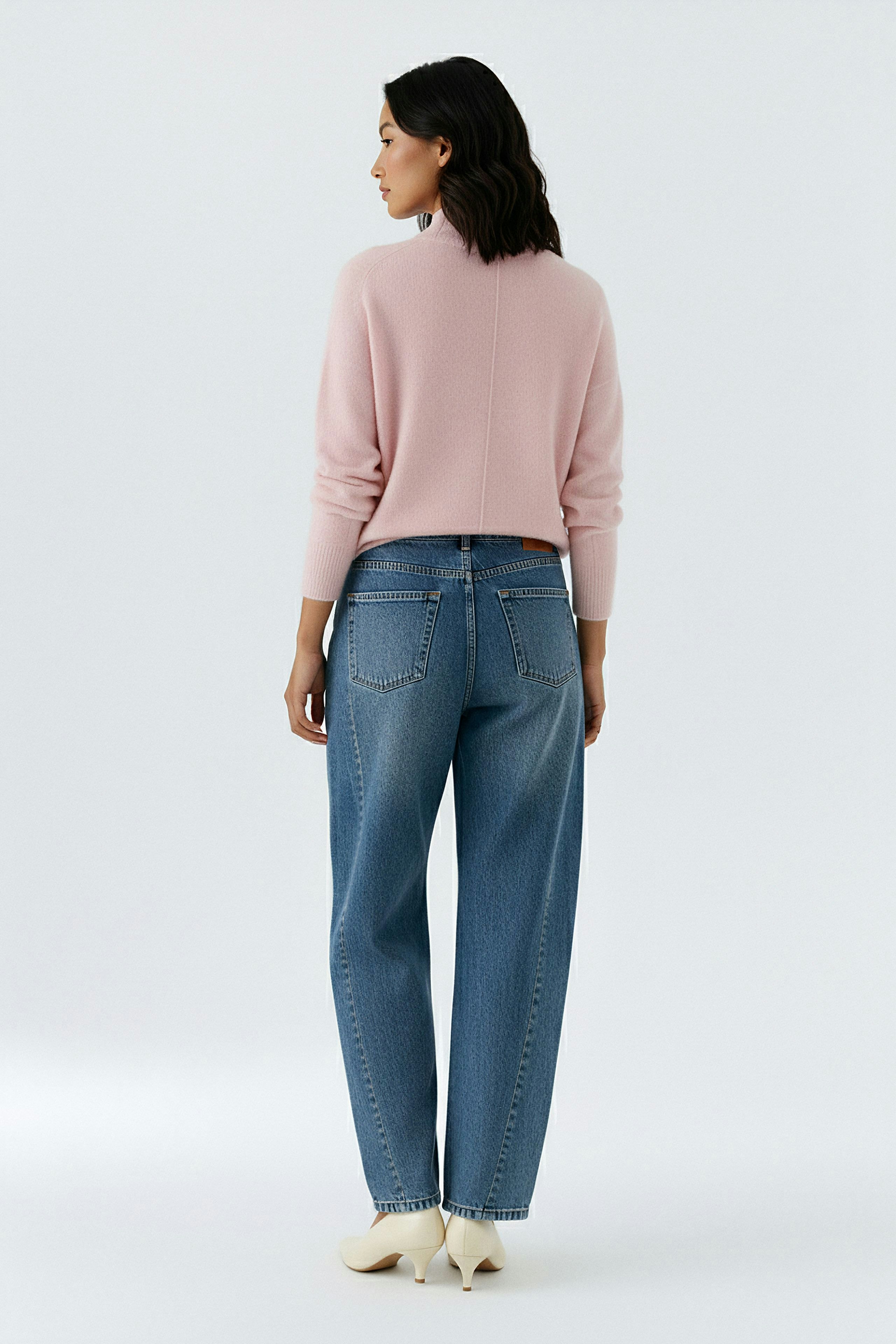 Damen-Pullover: Frau in rosa Strickpullover und lässigen Jeans von hinten.