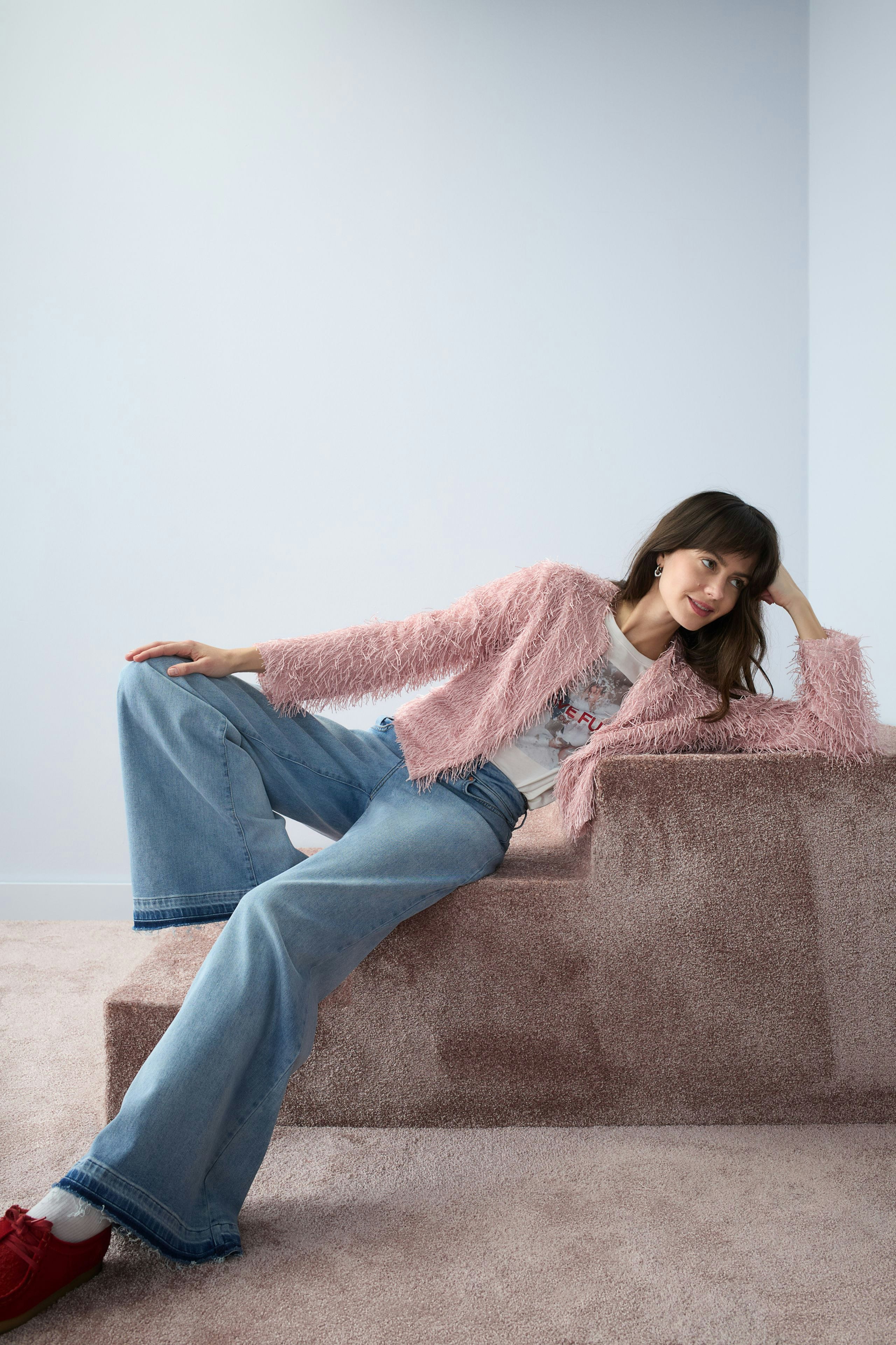Casual women's jacket: A woman in a fluffy pink jacket paired with wide-leg jeans, relaxed pose.