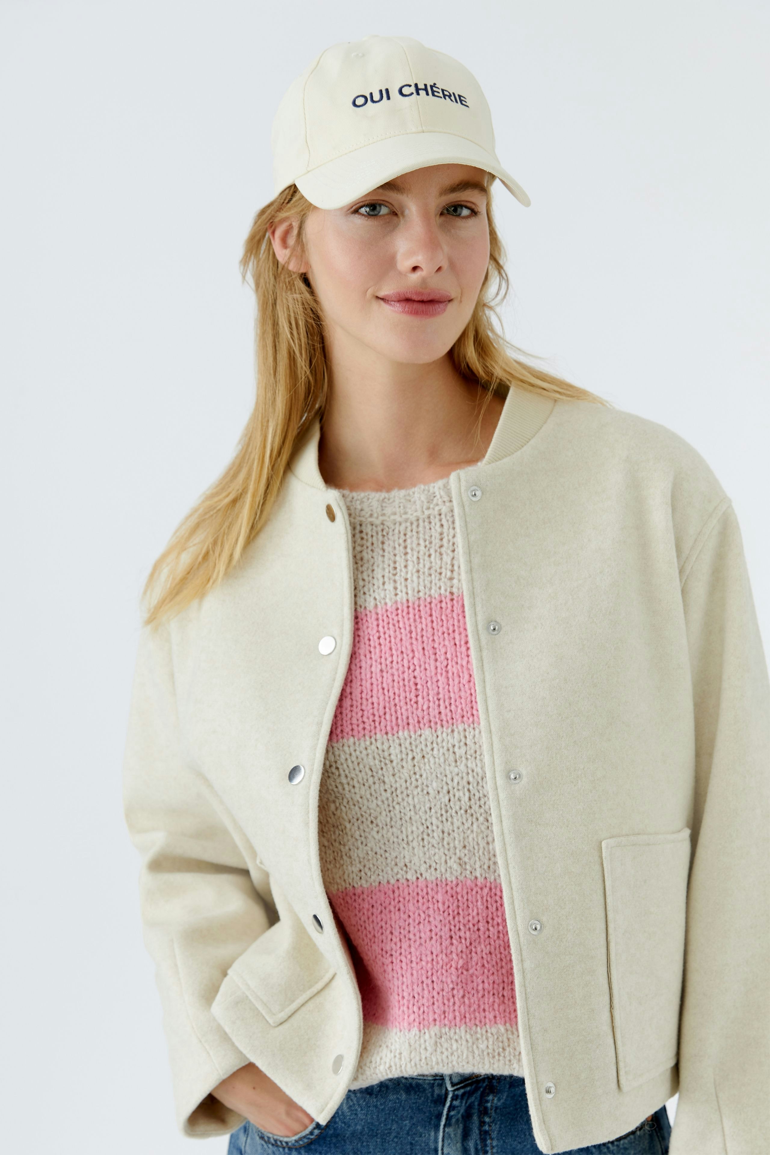 Casual women's hat: A woman wearing a beige cap with 'OUI CHÈRE' text, styled with a cozy pullover.