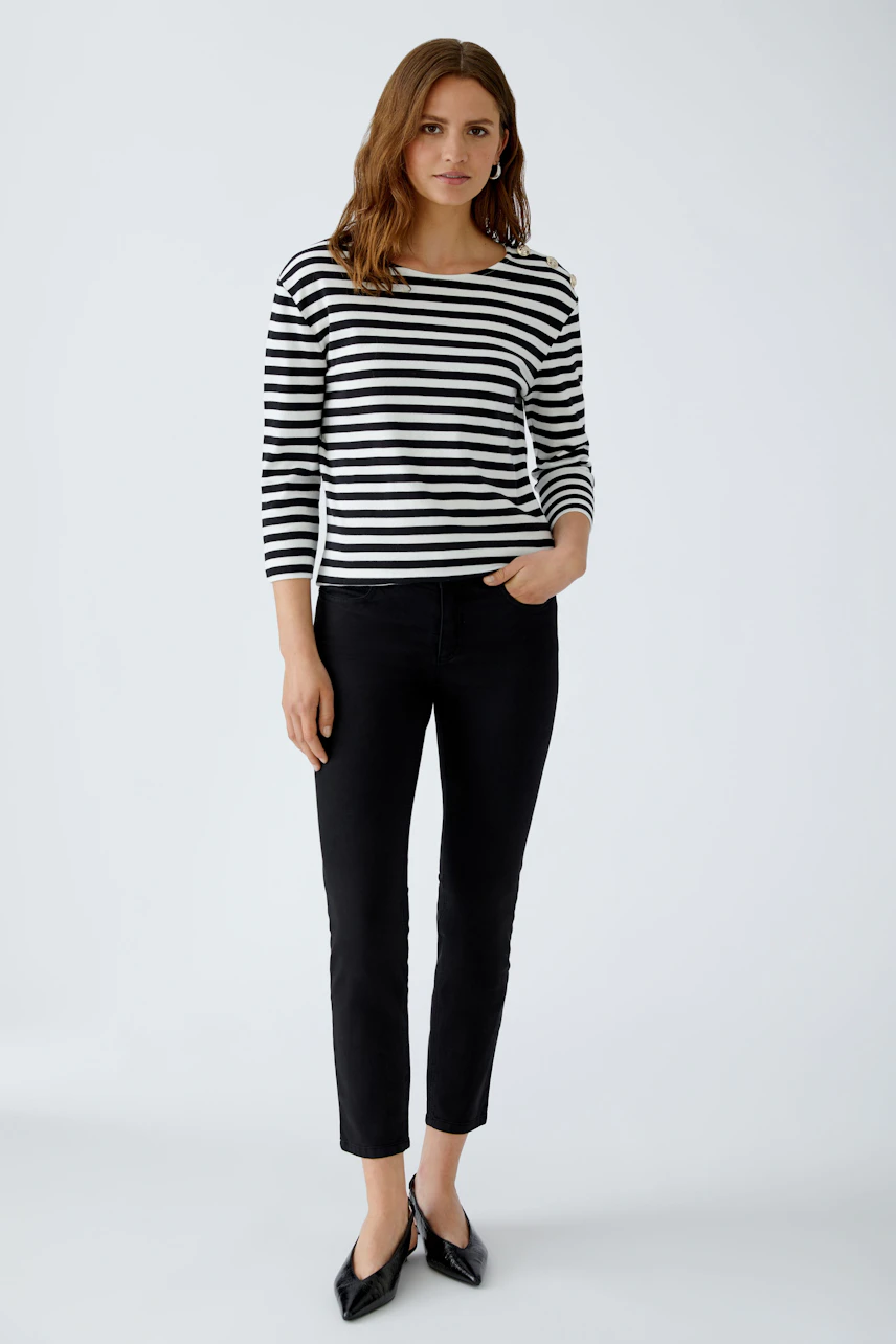 Stylish women's long-sleeve shirt: A woman in a striped top paired with flared jeans.