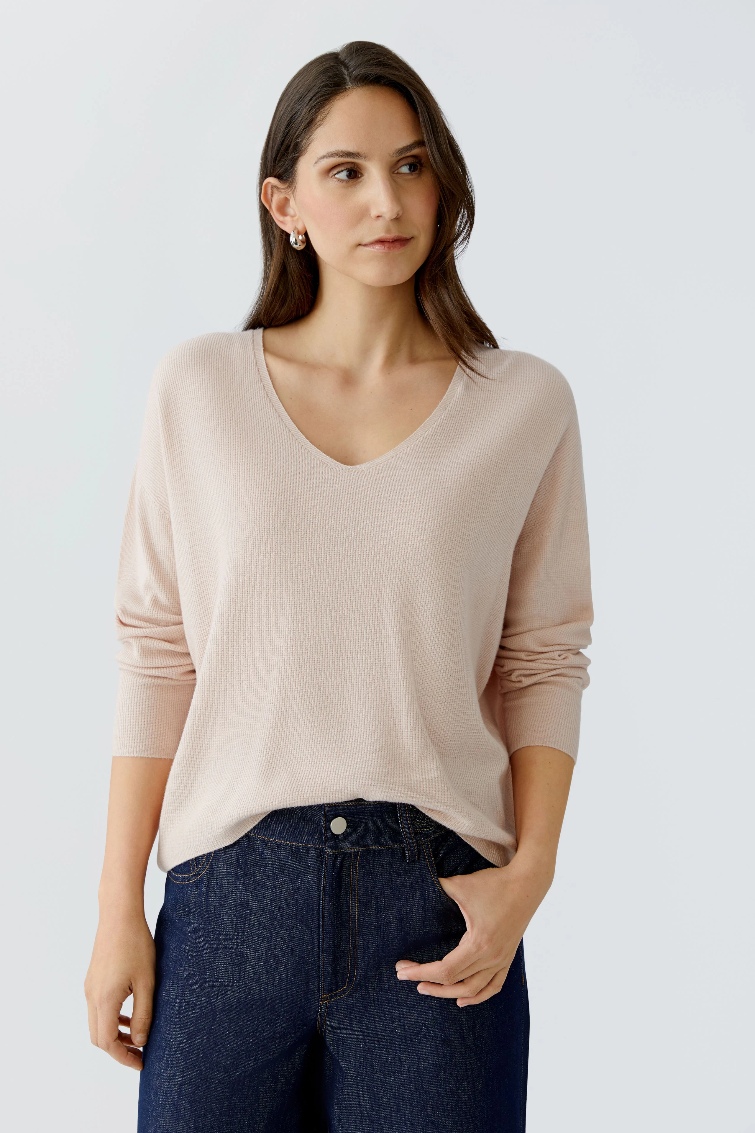 Bequemer Damen-Pullover in zartem Rosa, V-Ausschnitt, lässig kombiniert mit Jeans.
