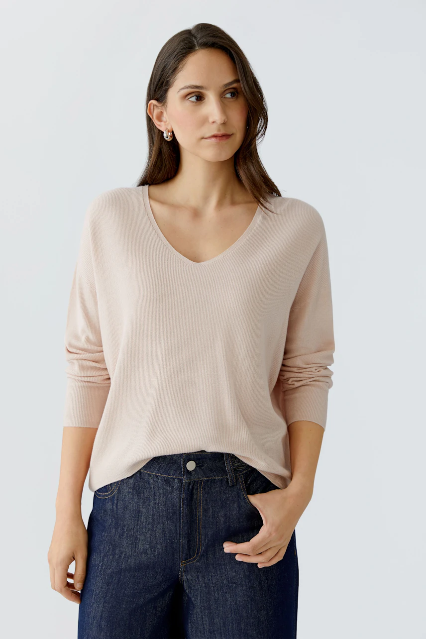 Bequemer Damen-Pullover in zartem Rosa, V-Ausschnitt, lässig kombiniert mit Jeans.