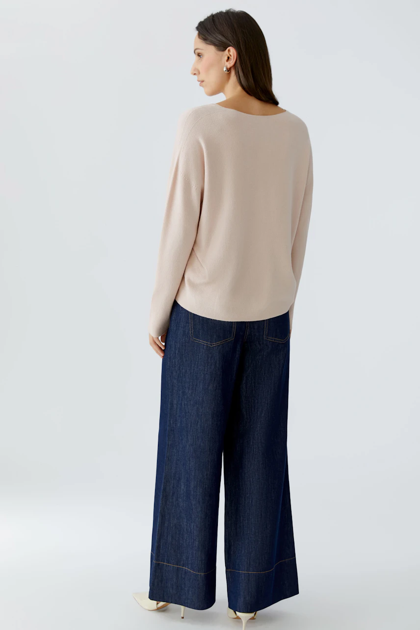 Bequemer Damen-Pullover in zartem Beige, kombiniert mit lässigen Jeans und flachen Schuhen.