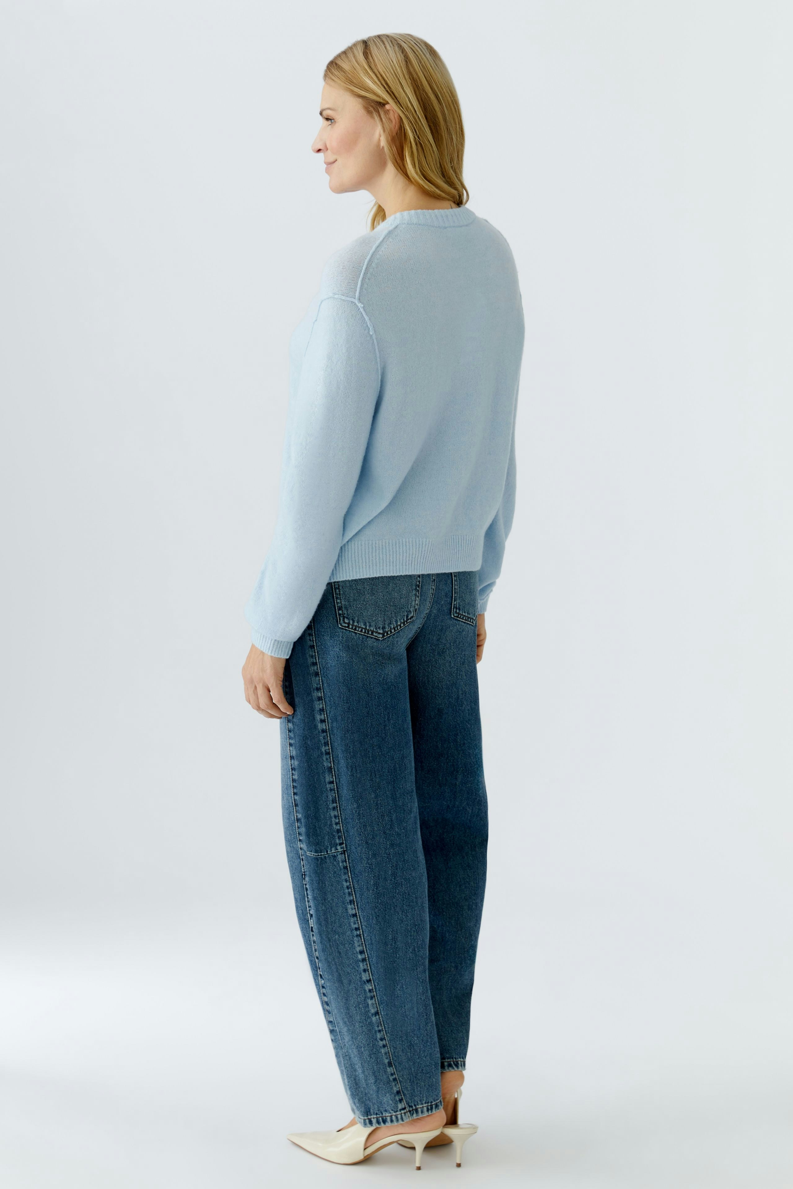 Casual women's cardigan: A woman in a light blue cardigan paired with relaxed jeans, showcasing a comfortable style.