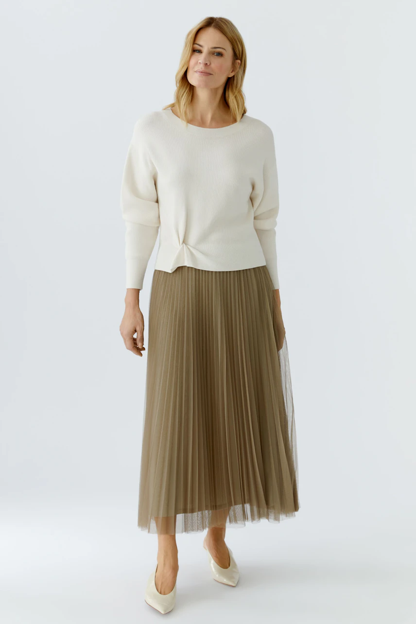 Casual pleated skirt: Woman in a light sweater and a flowing pleated skirt, showcasing a relaxed style.