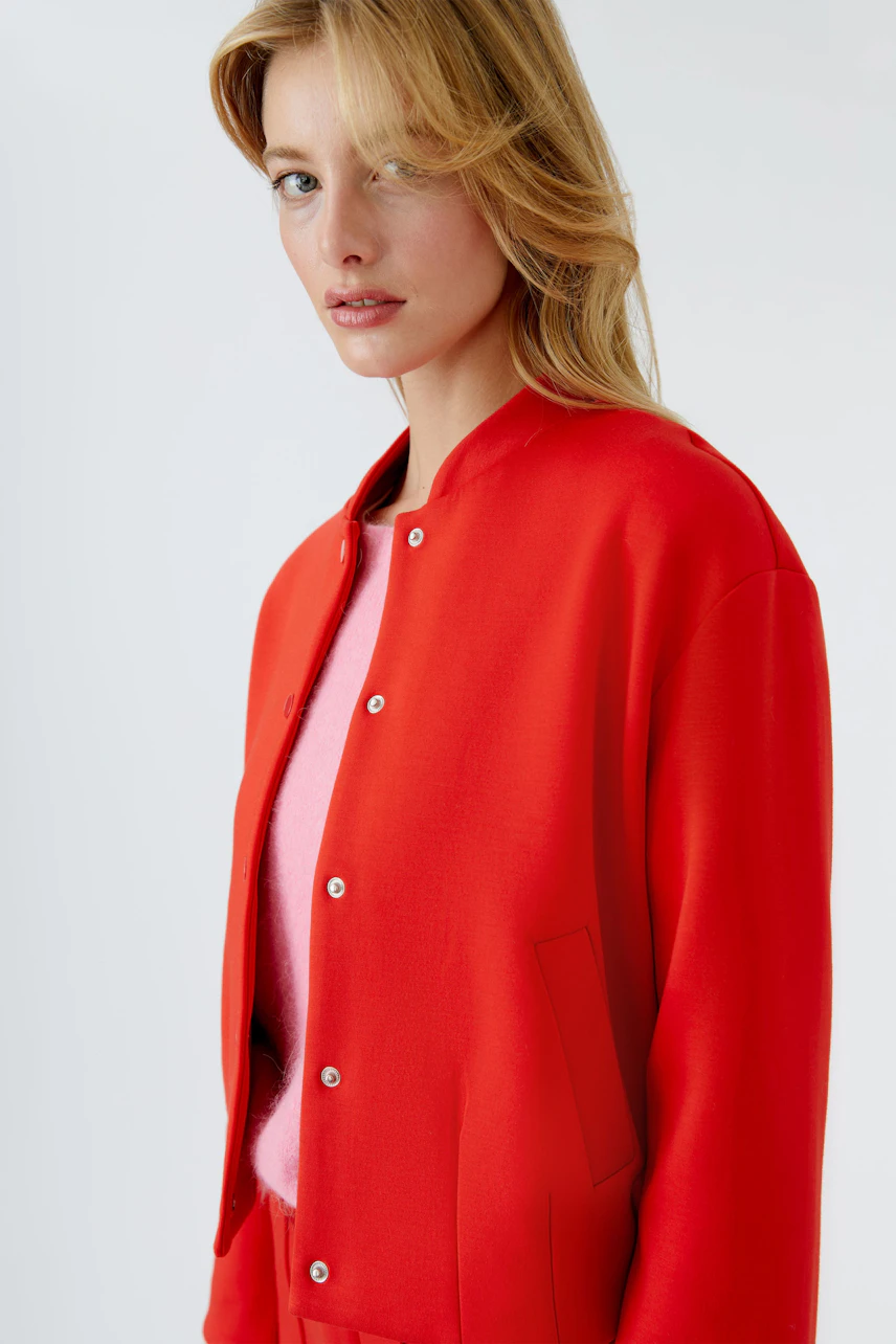 Damen-Blouson: Frau in rotem Blouson mit Druckknöpfen und lässigem Look.
