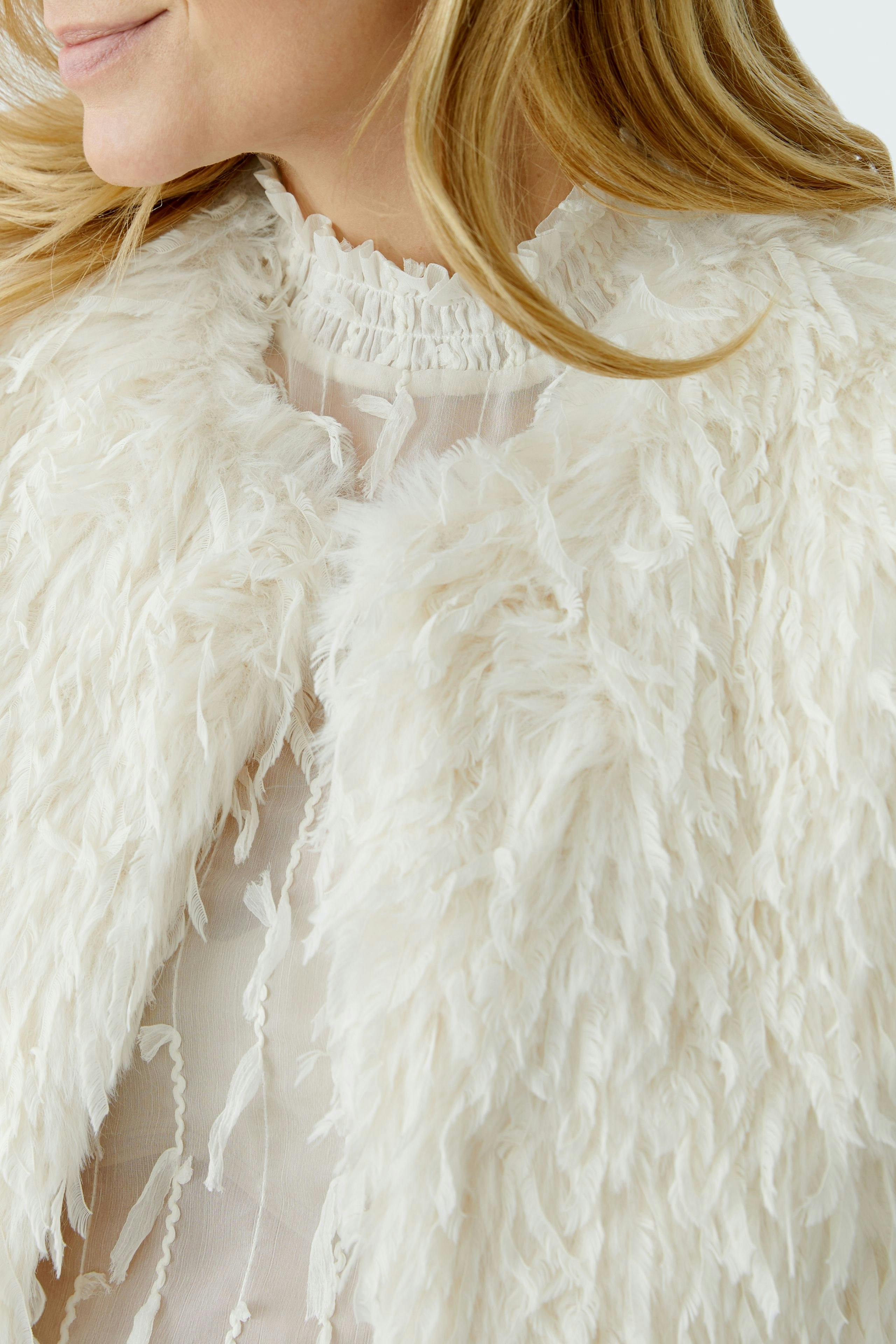 Cozy women's vest: A woman in a fluffy white vest over a sheer top, showcasing a relaxed style.