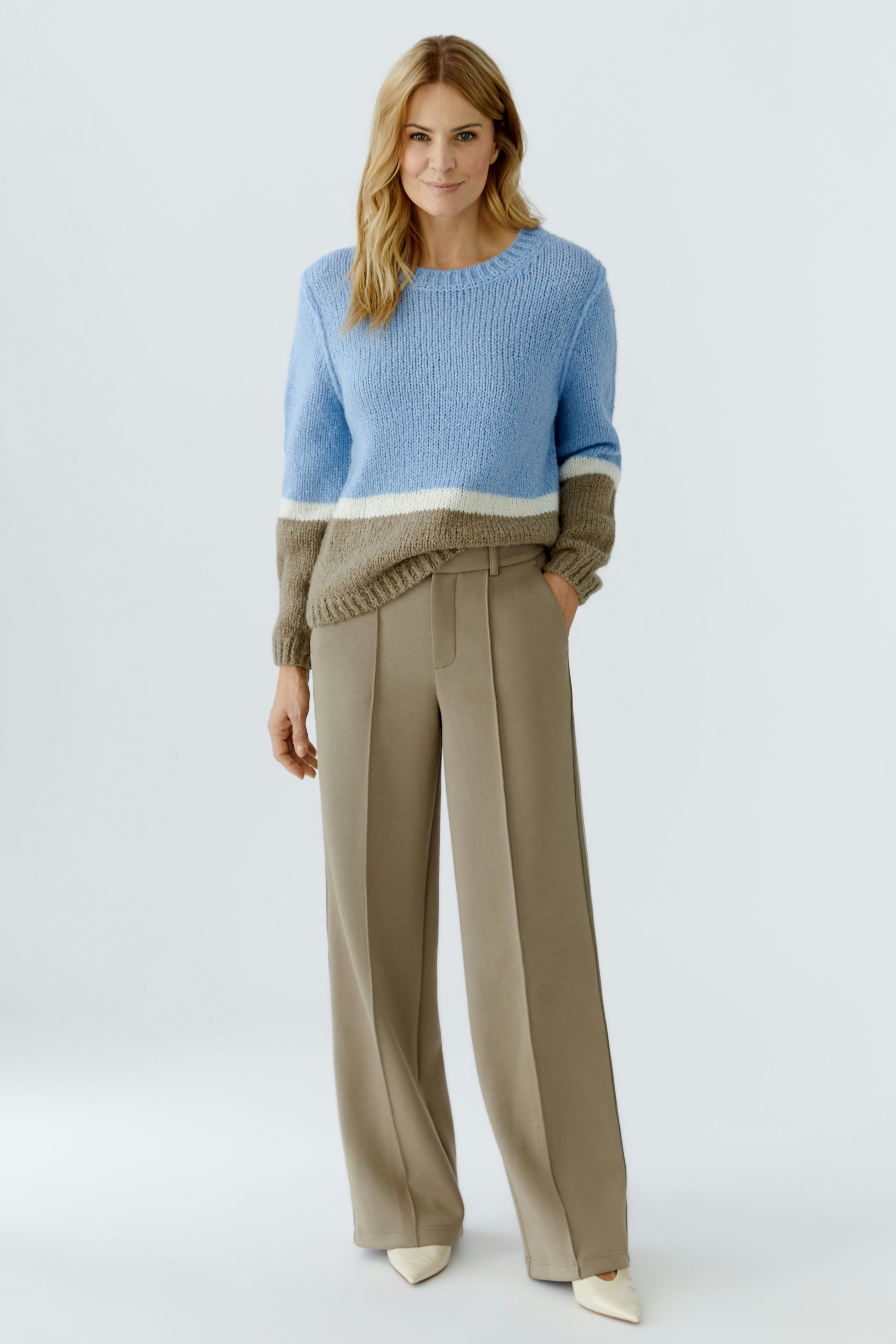 Casual women's trousers: A woman in beige wide-leg trousers and a blue pullover smiles confidently.