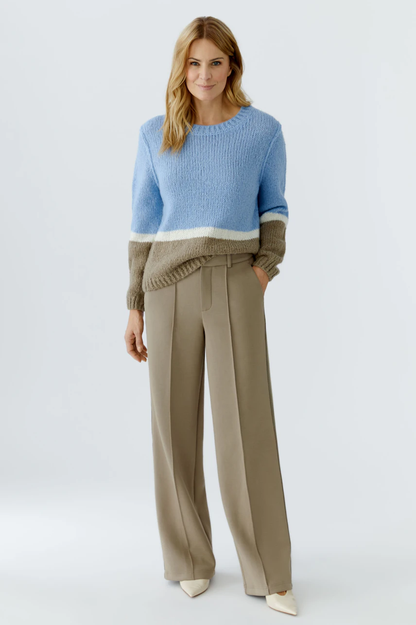Casual women's trousers: A woman in beige wide-leg trousers and a blue pullover smiles confidently.