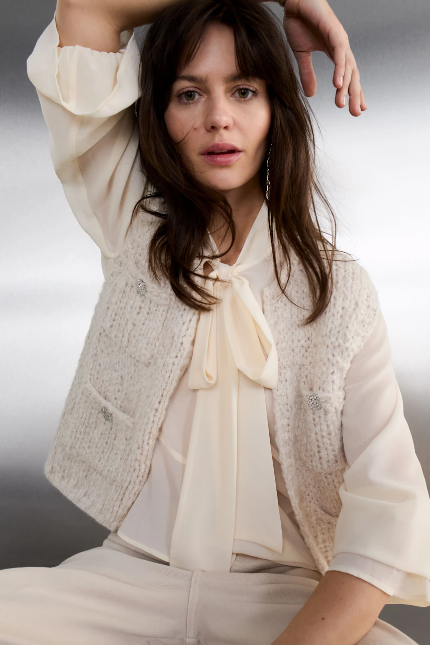 Casual women's blouse: Woman in a vibrant red knit blouse with a stylish bow detail.