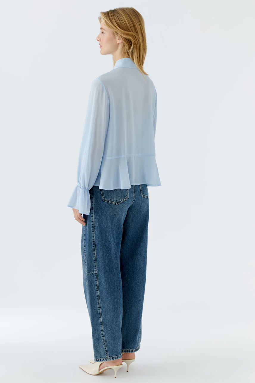 Leichte Damen-Bluse in Hellblau, mit weiten Ärmeln und fließendem Schnitt, kombiniert mit lässigen Jeans.