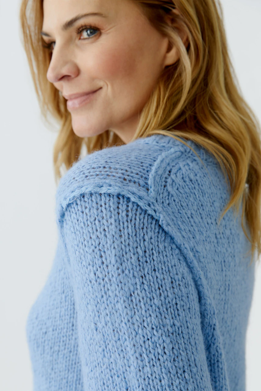 Casual women's pullover: Woman in a light blue knitted pullover with a relaxed fit, smiling softly.